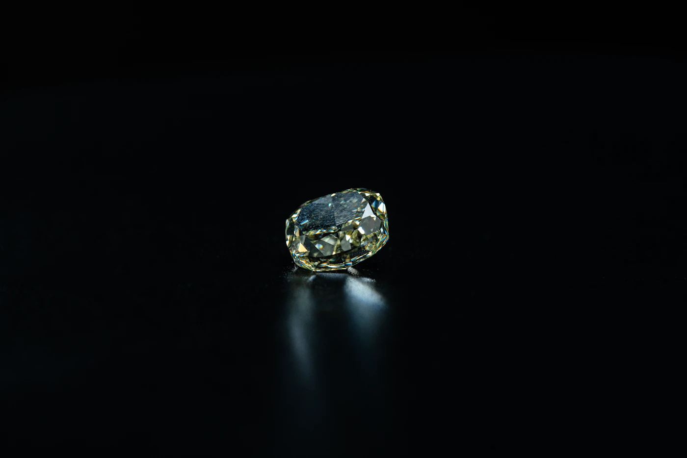 Faceted diamond with a warm yellow tint on a black background