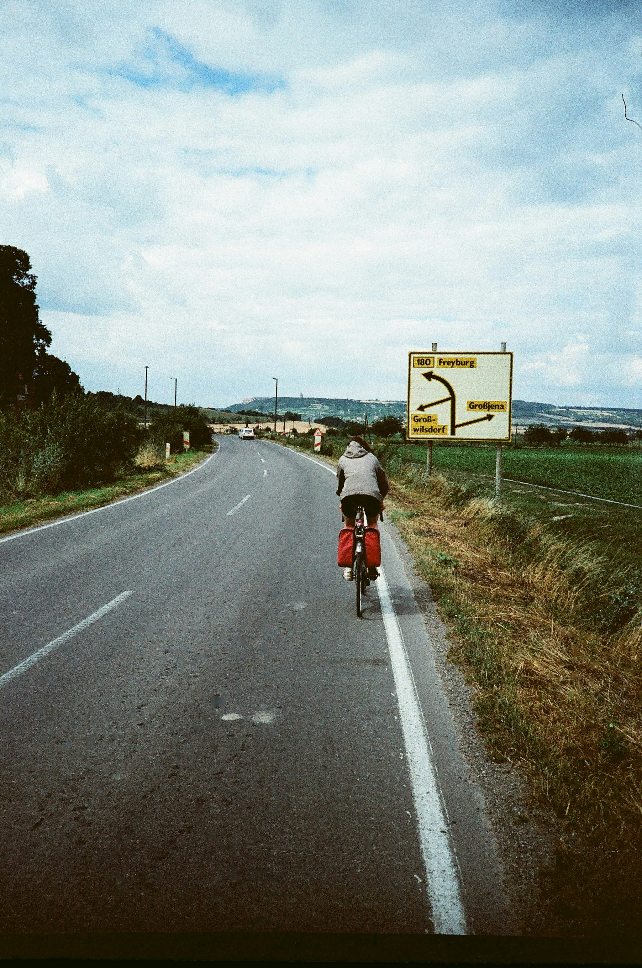A cyclist rides down a road toward directions.