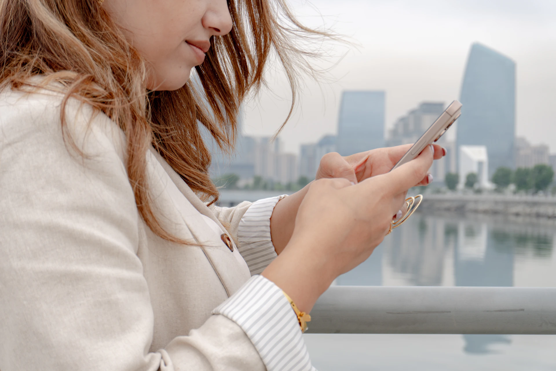 Woman uses her phone in a cityscape.