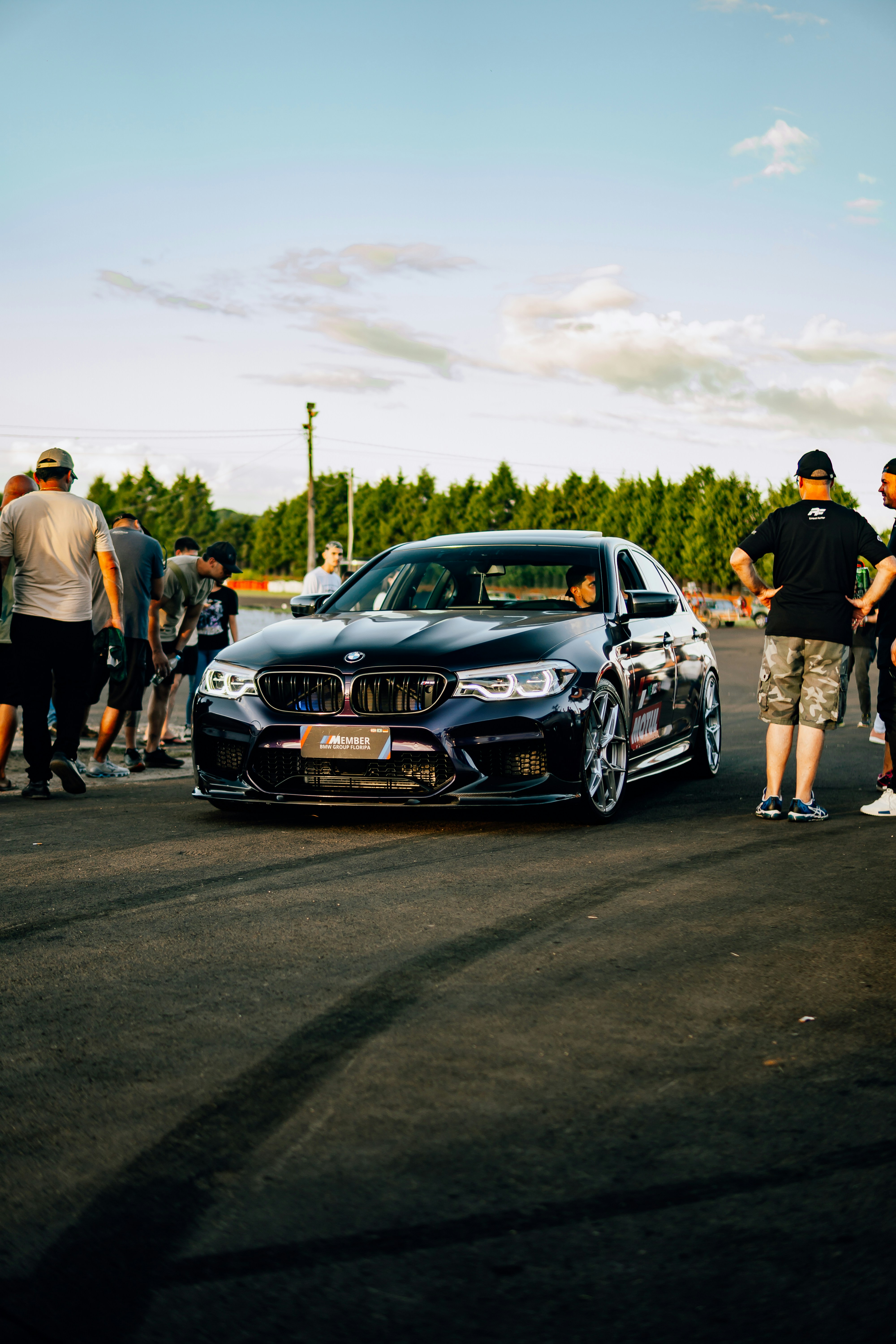 A black BMW car is surrounded by people.