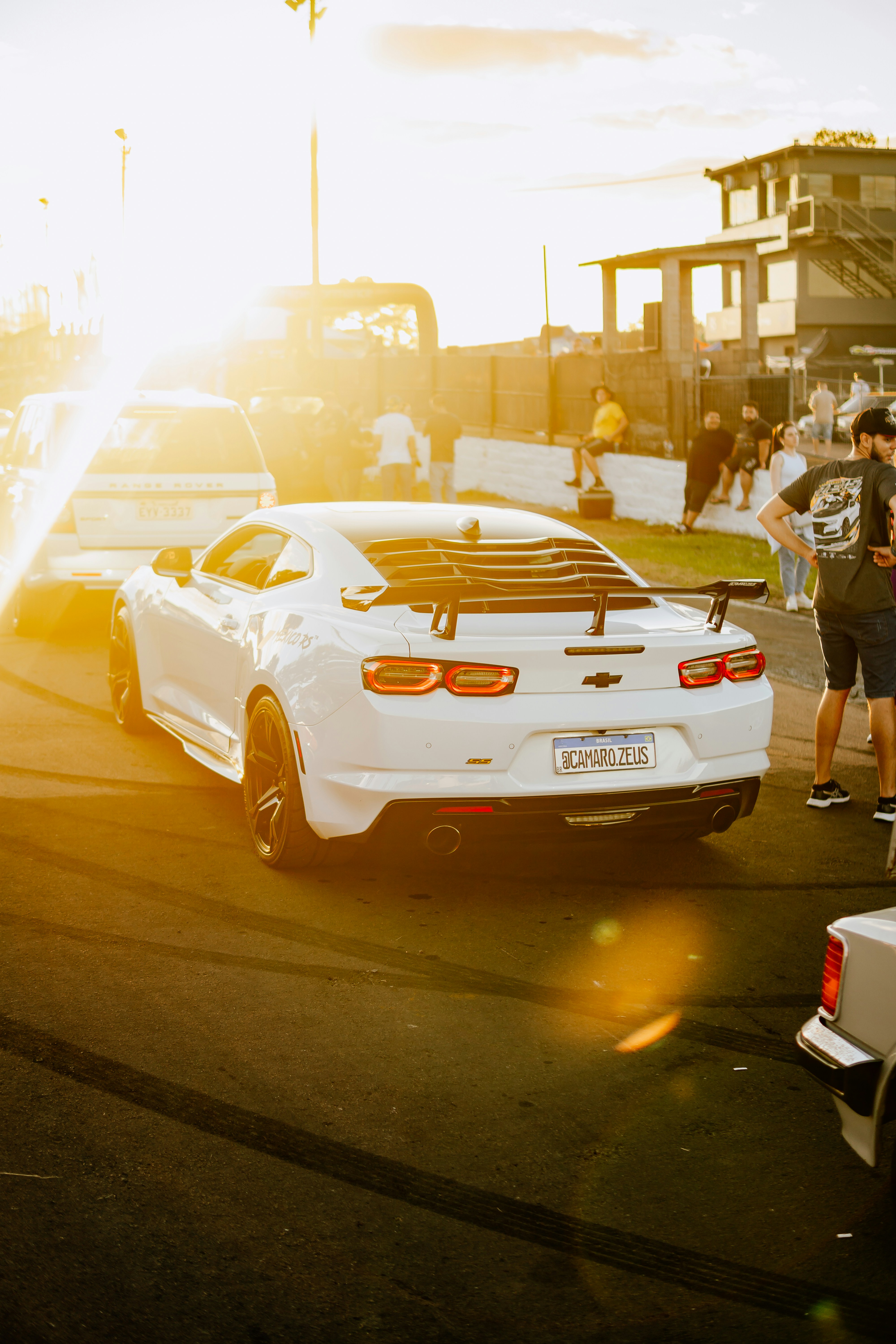 A white car sits on a racetrack at sunset.