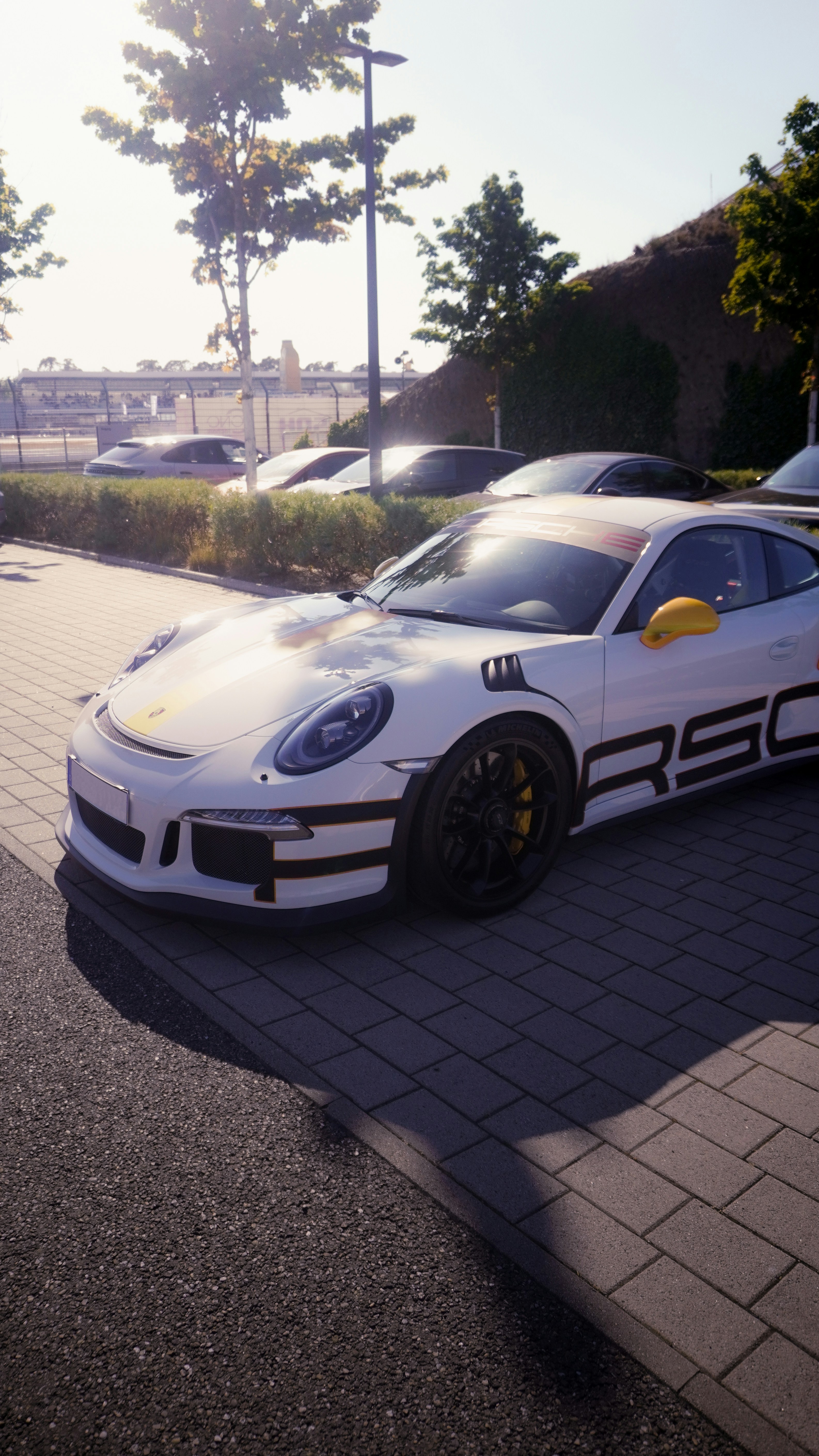 A white porsche sports car is parked outside.