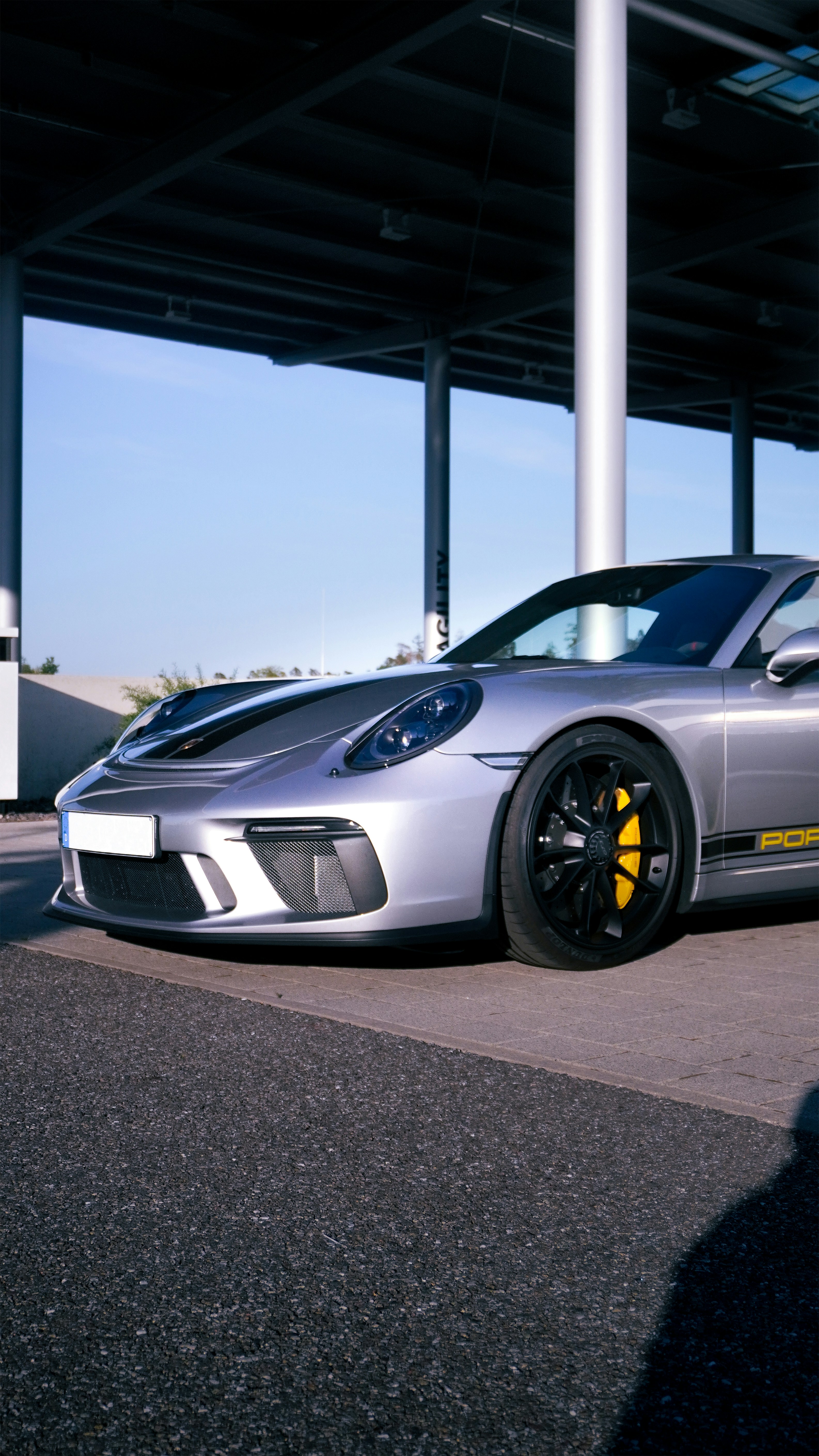 Ein silberner Porsche-Sportwagen parkt im Freien.