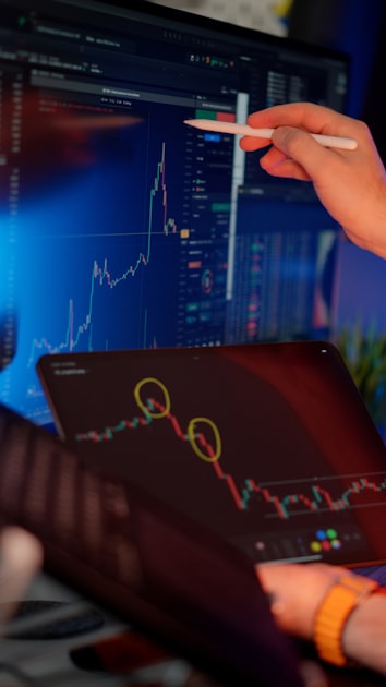 A developer at a workstation reviewing financial data and charts on multiple monitors