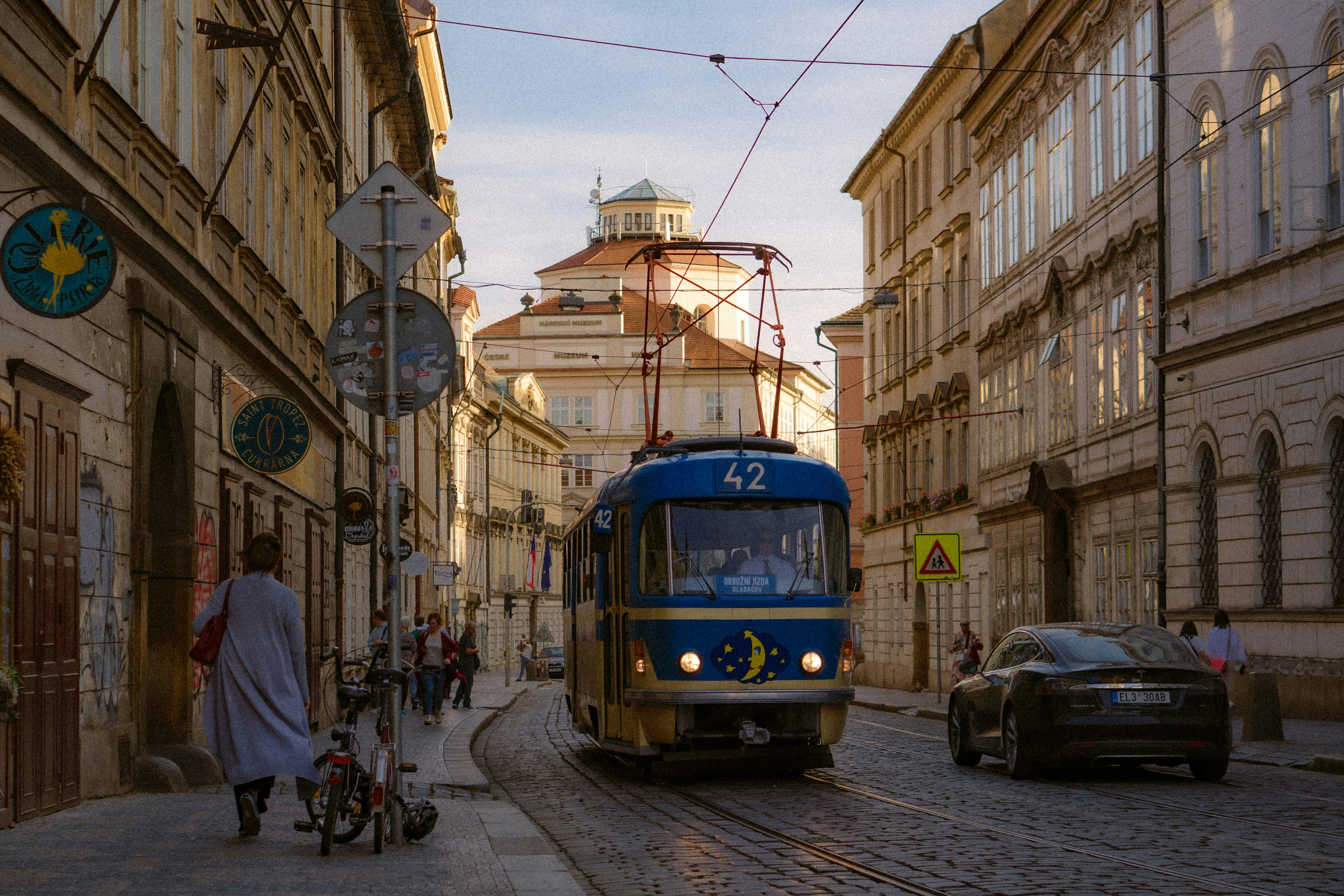 A blue tram travels down a historic city street.