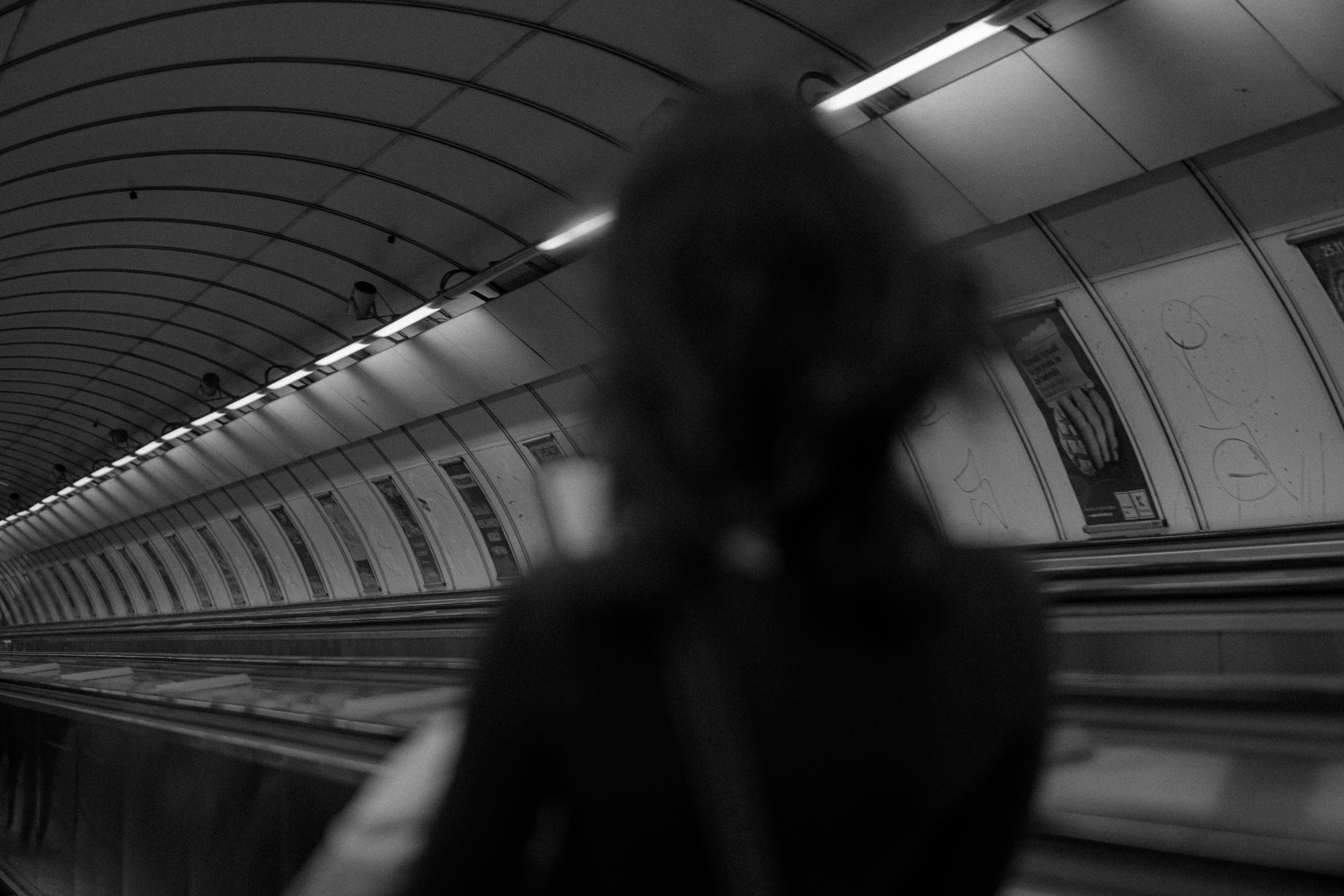 Person rides the escalator down a long tunnel.