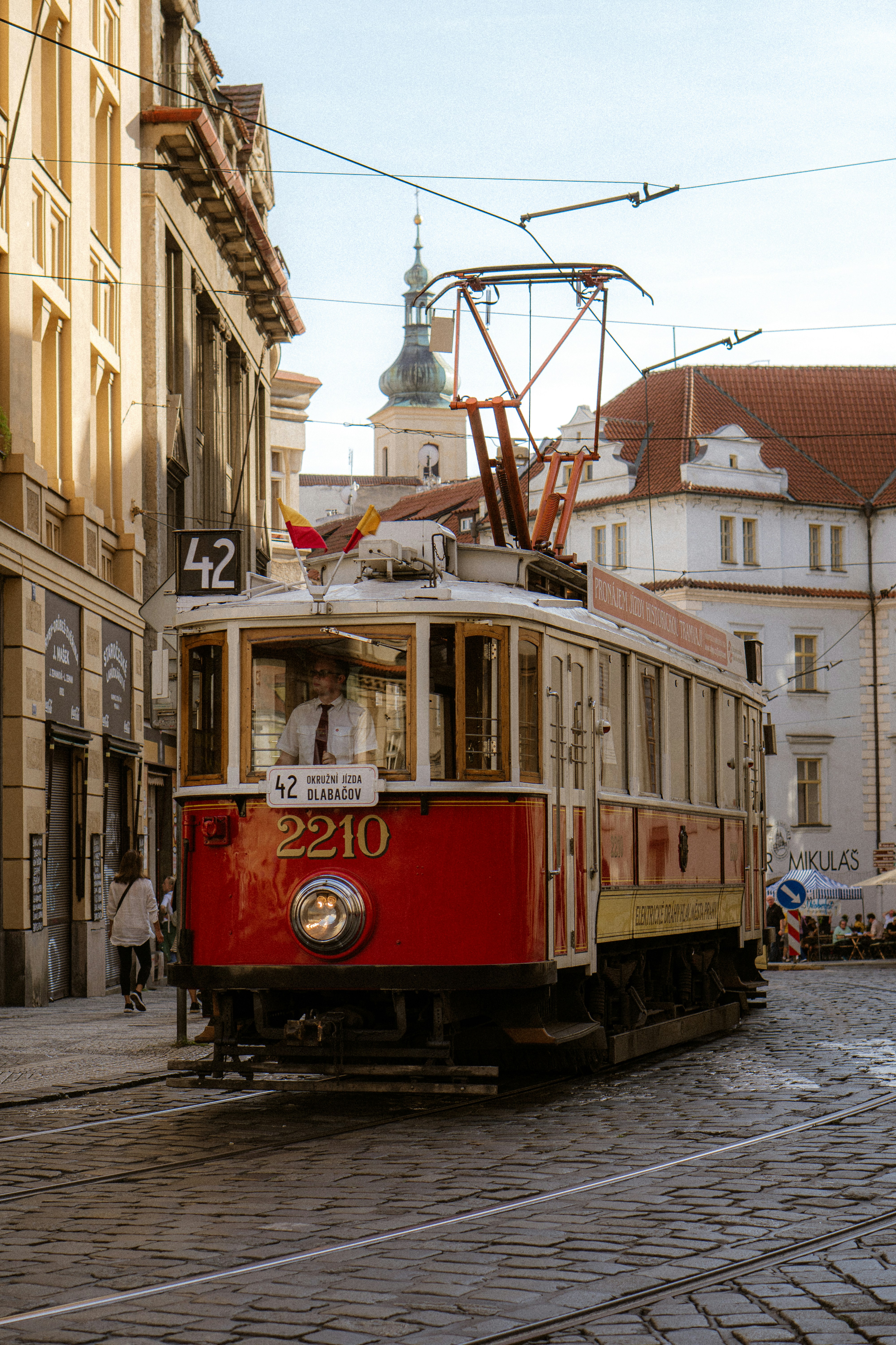 A classic tram rolls down a cobblestone street.