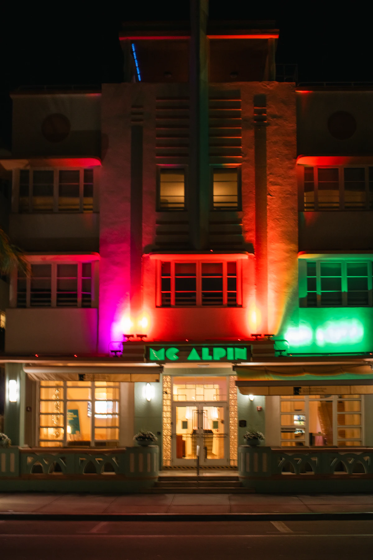 Art Deco hotel facade glowing with red and green neon at night on Ocean Drive
