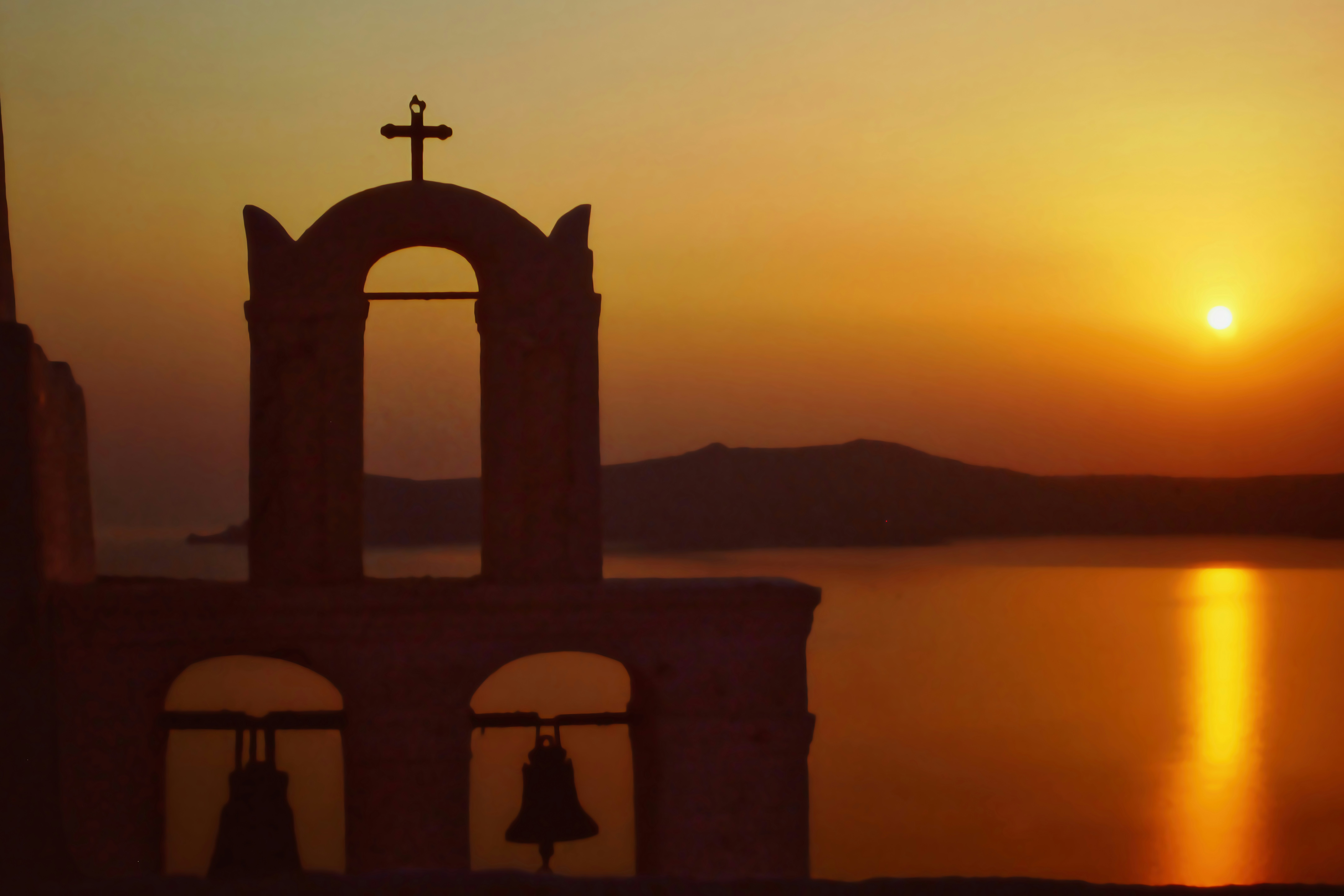 Church bell tower silhouetted by a sunset.