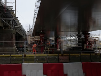 Construction workers work under a large bridge.