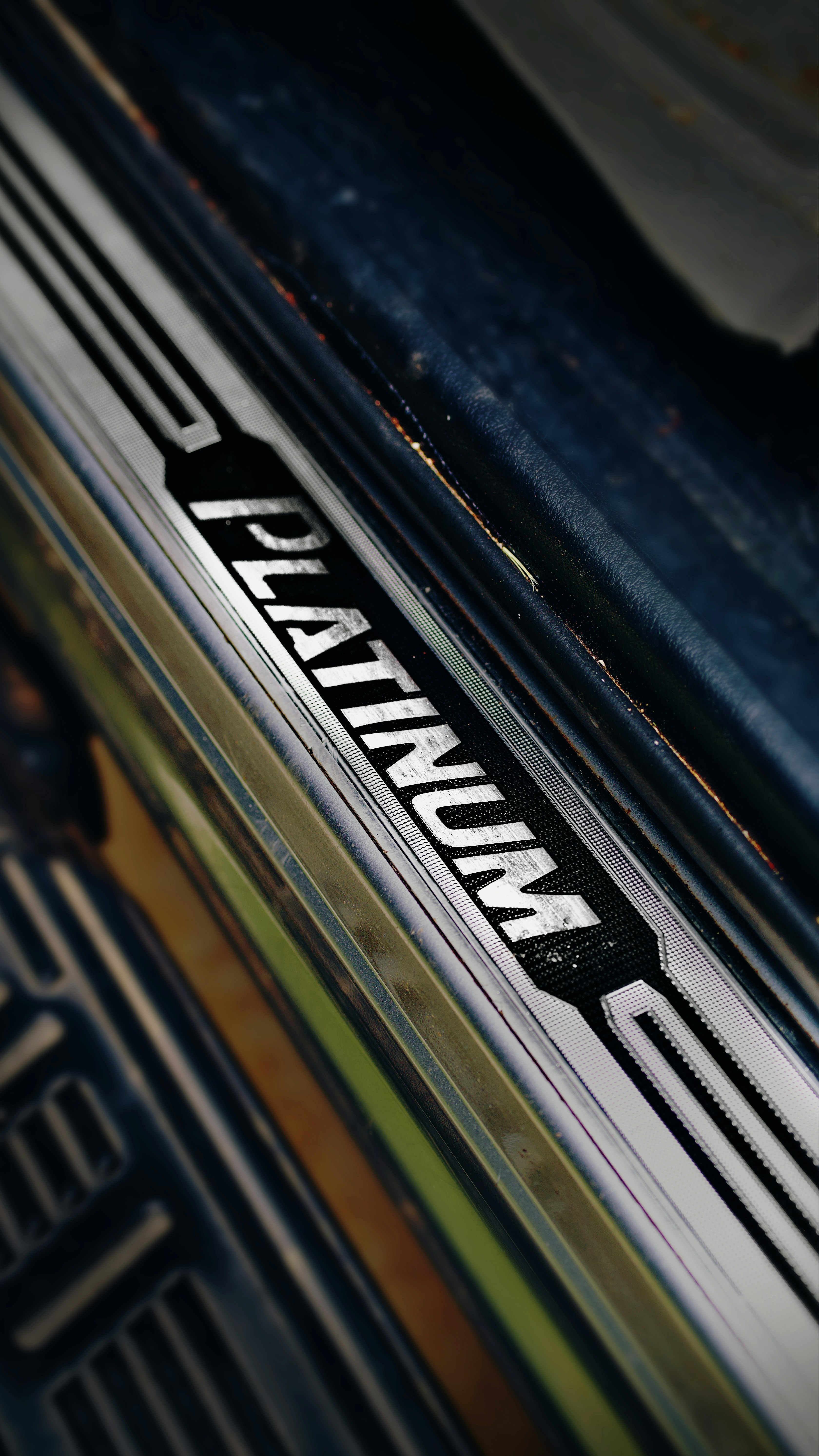 Platinum trim door-sill plate on a vehicle, lettering pressed into brushed metal, shot in close crop.