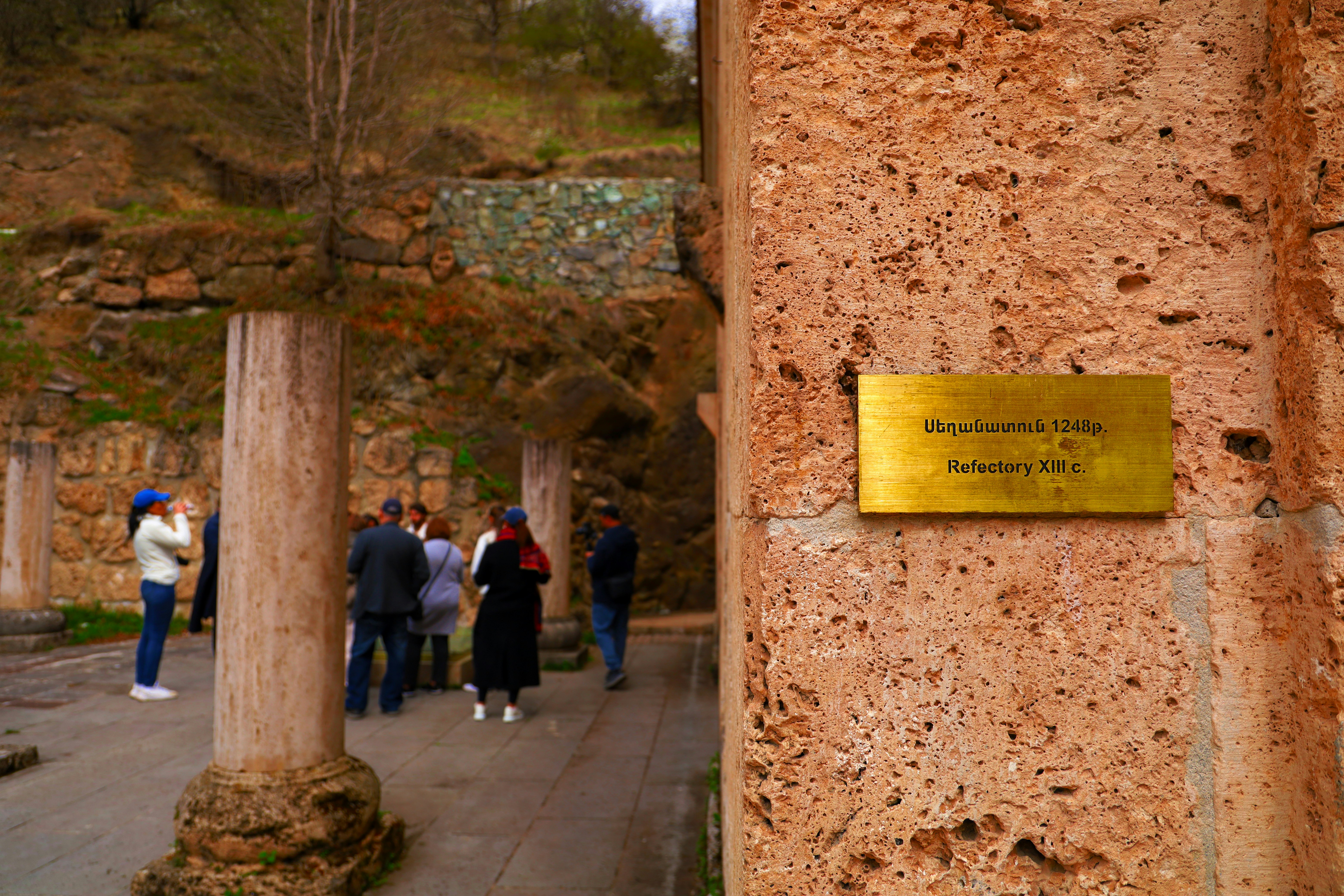Personnes visitant un site sous une colonnade en pierre près d une plaque