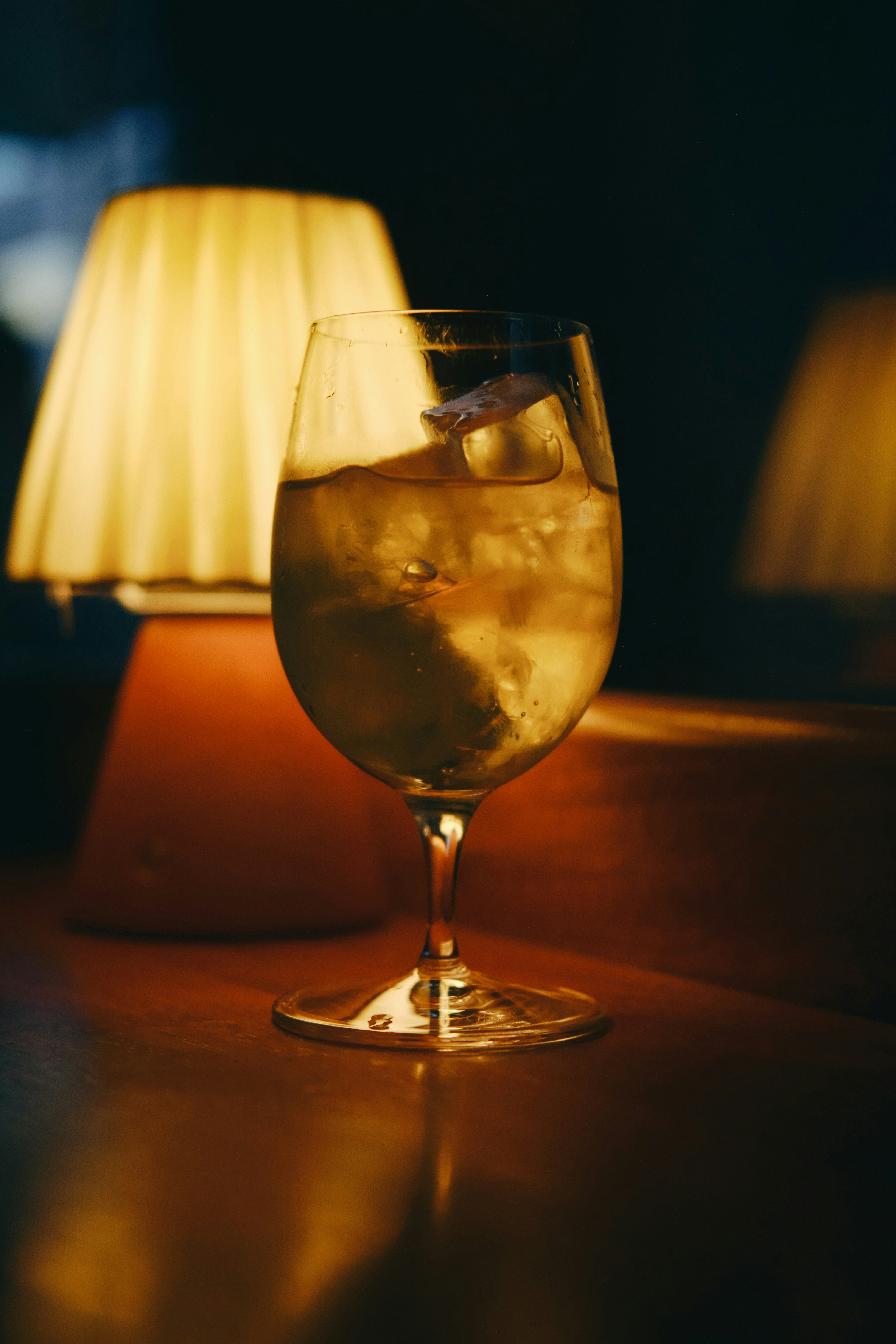 A glass of drink sits beside a lamp.
