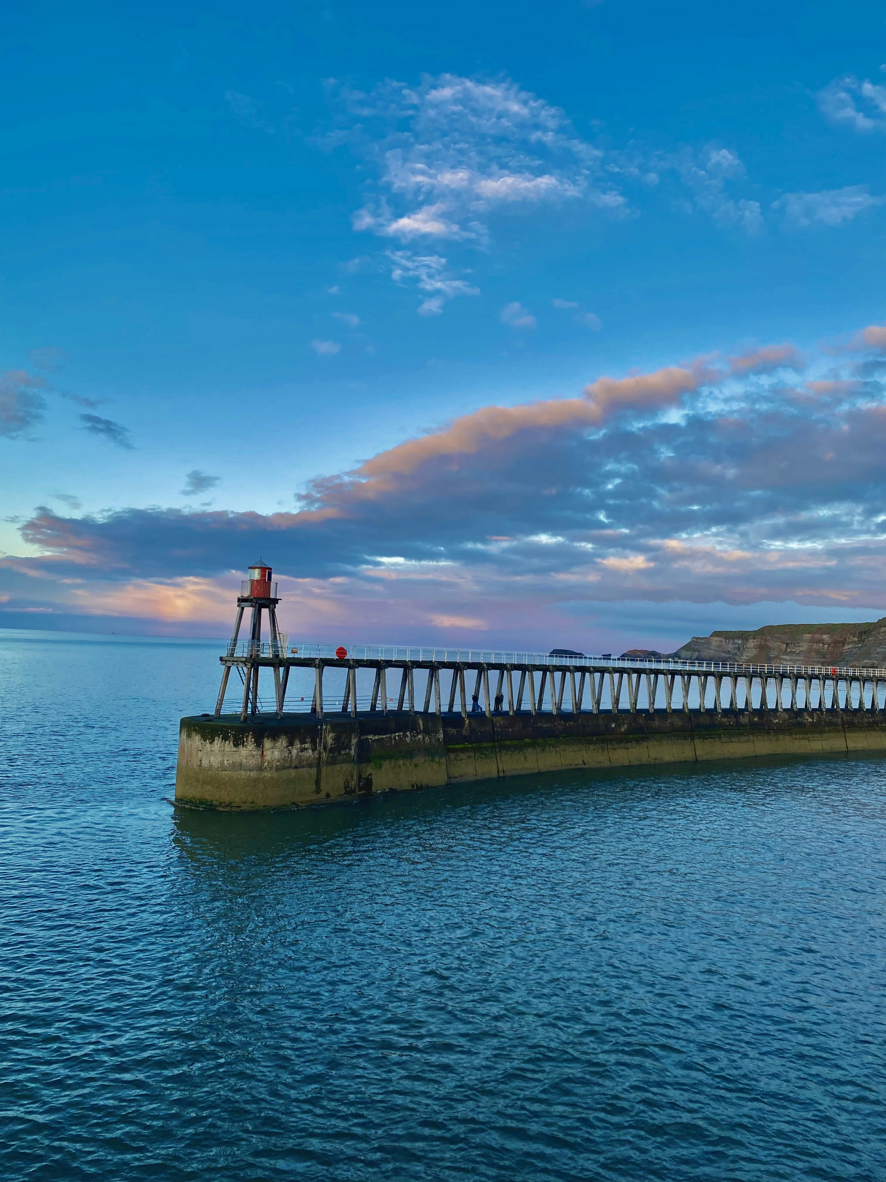 A lighthouse stands on a pier at twilight.