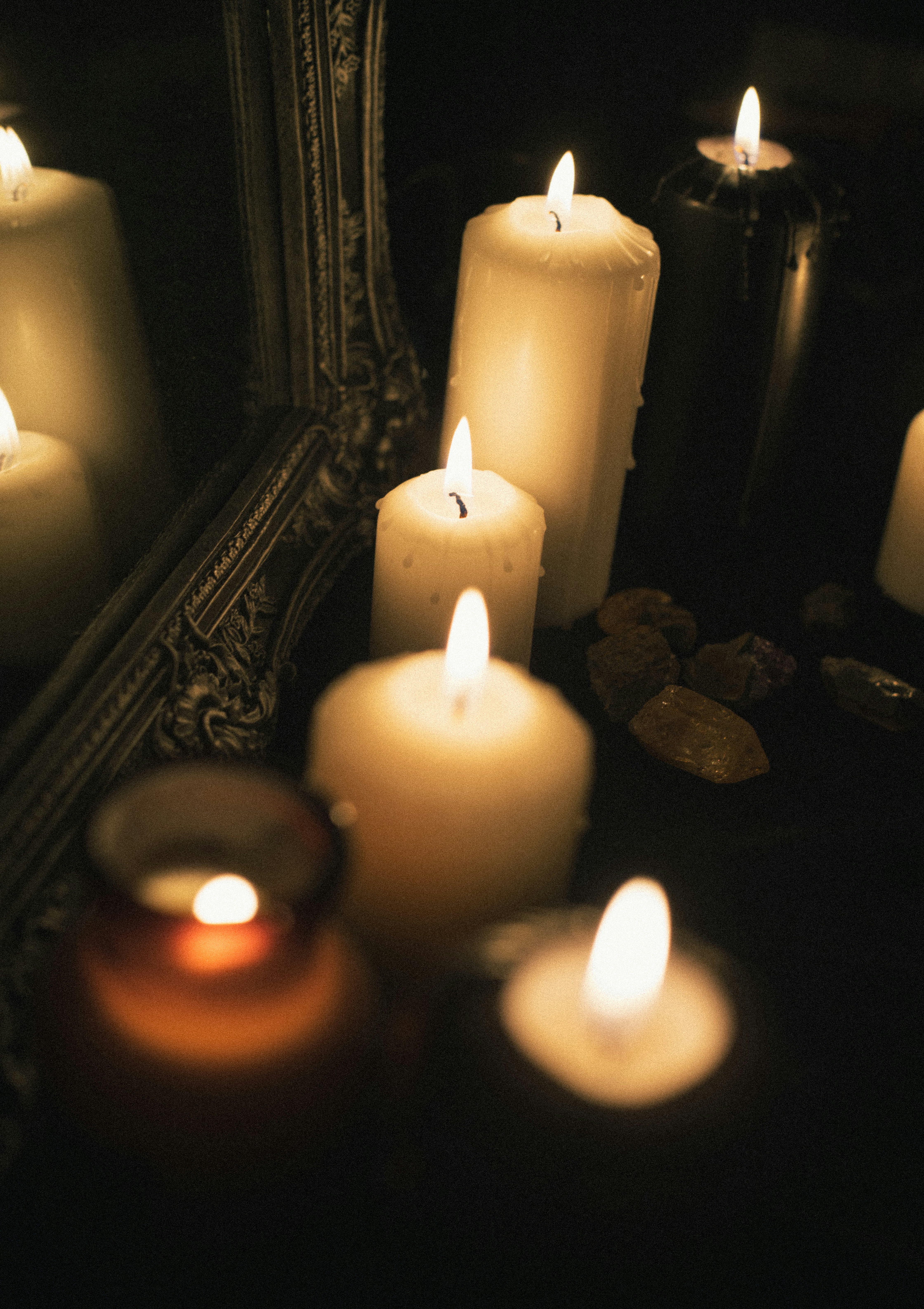 Burning candles are reflected in an antique mirror.
