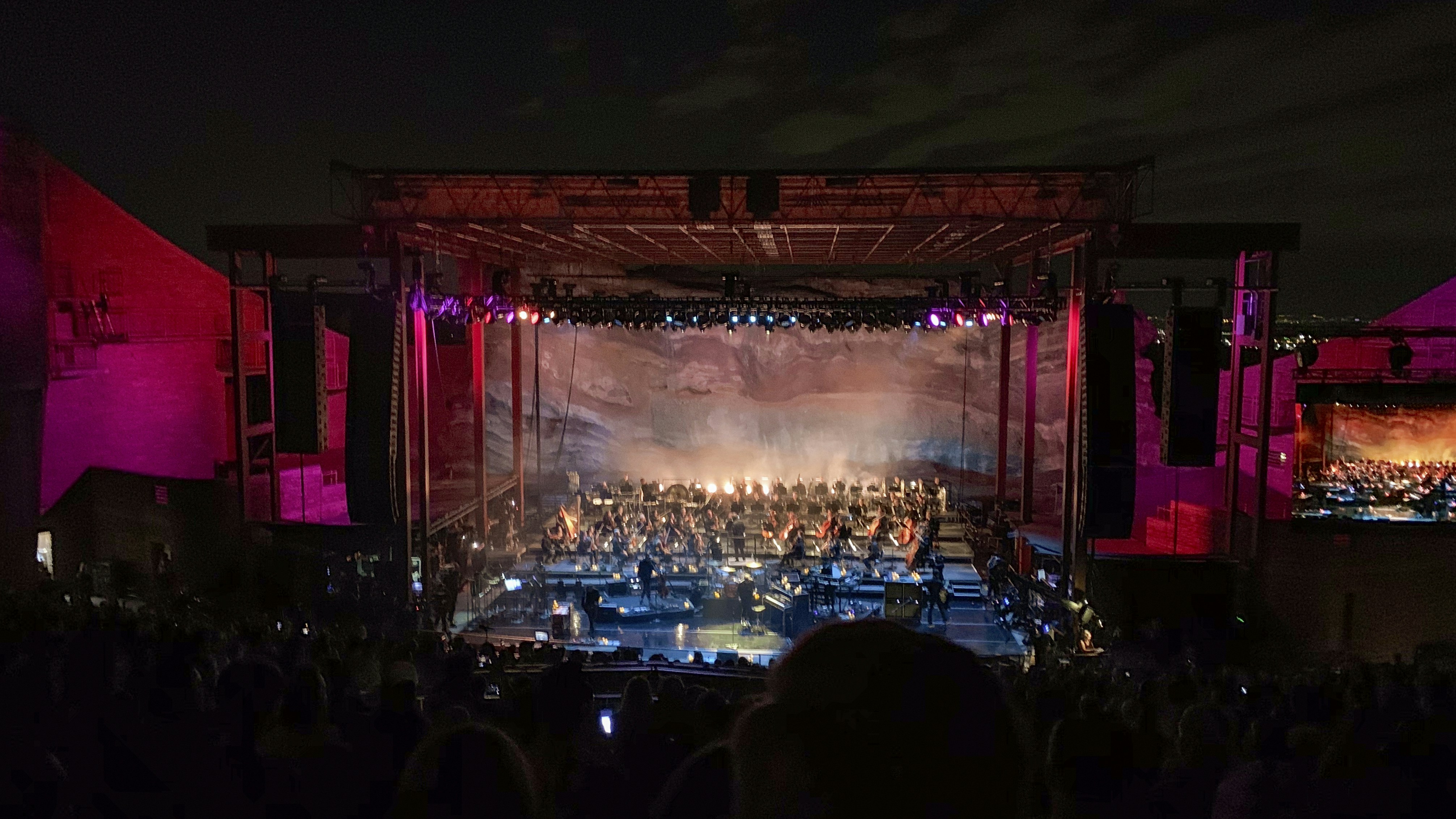 An orchestra is performing on stage under the lights.