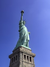 The statue of liberty stands tall against the blue sky.