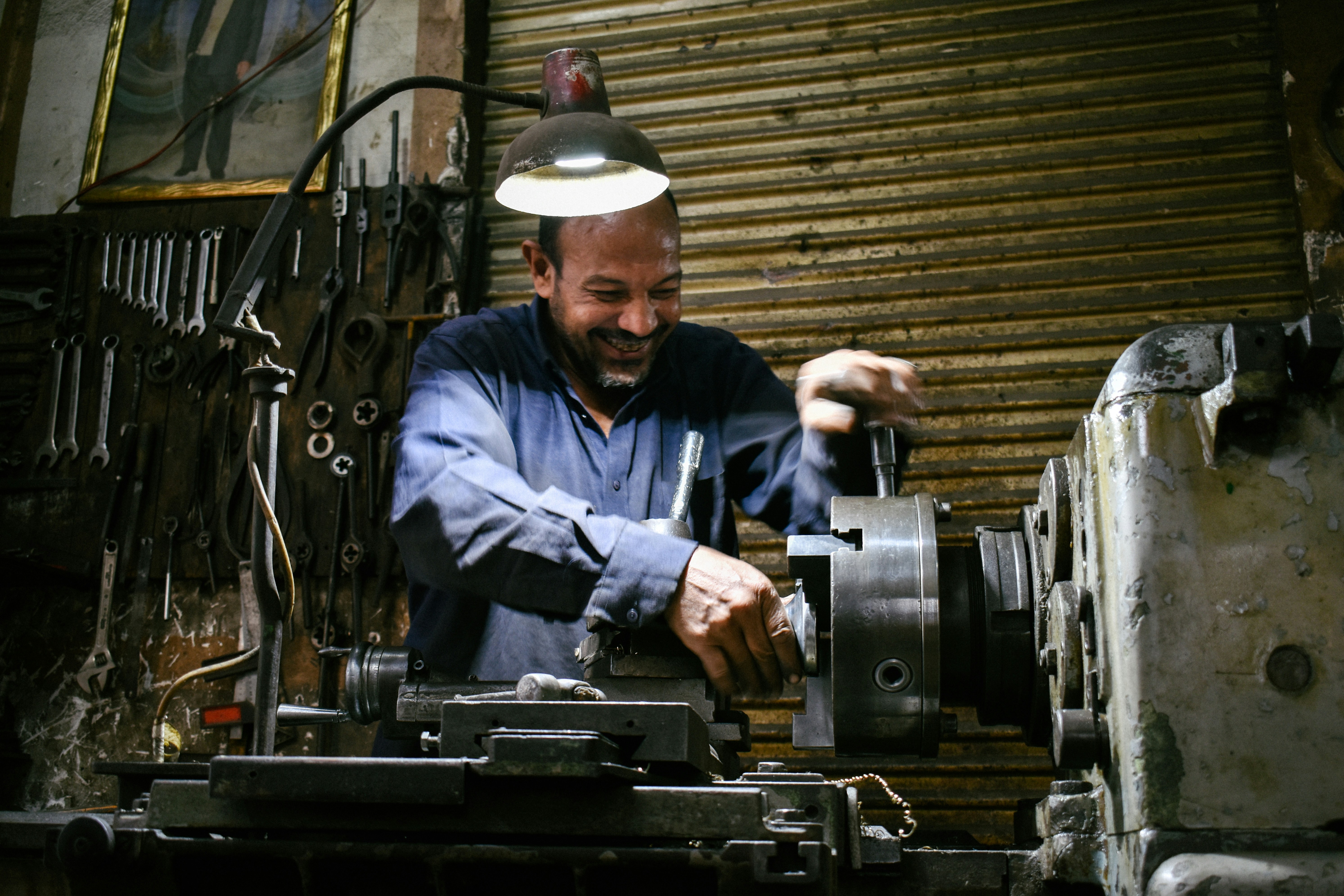 A smiling machinist works in a workshop.