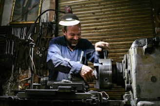 A smiling machinist works in a workshop.