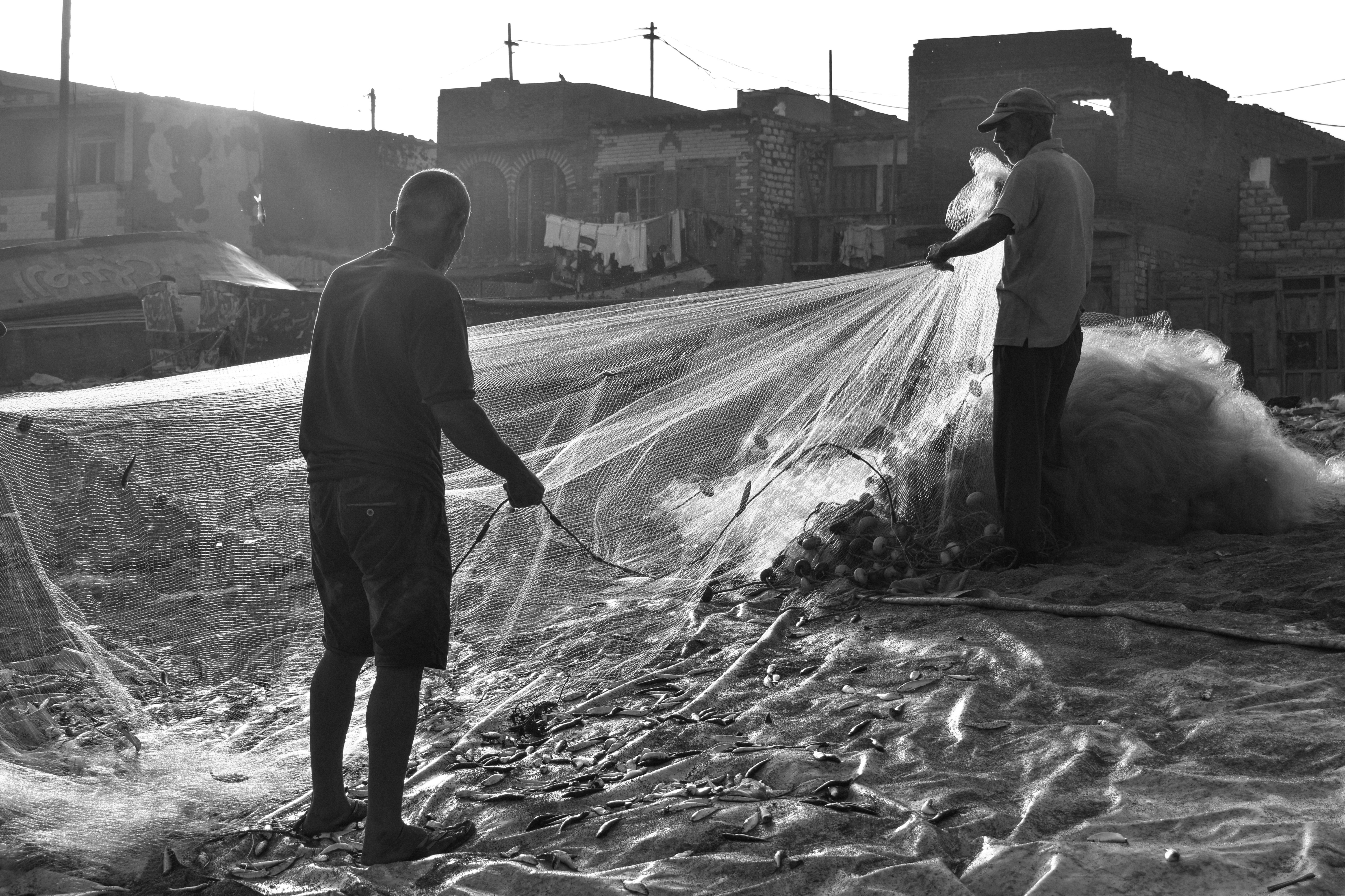 Two fishermen prepare their nets.