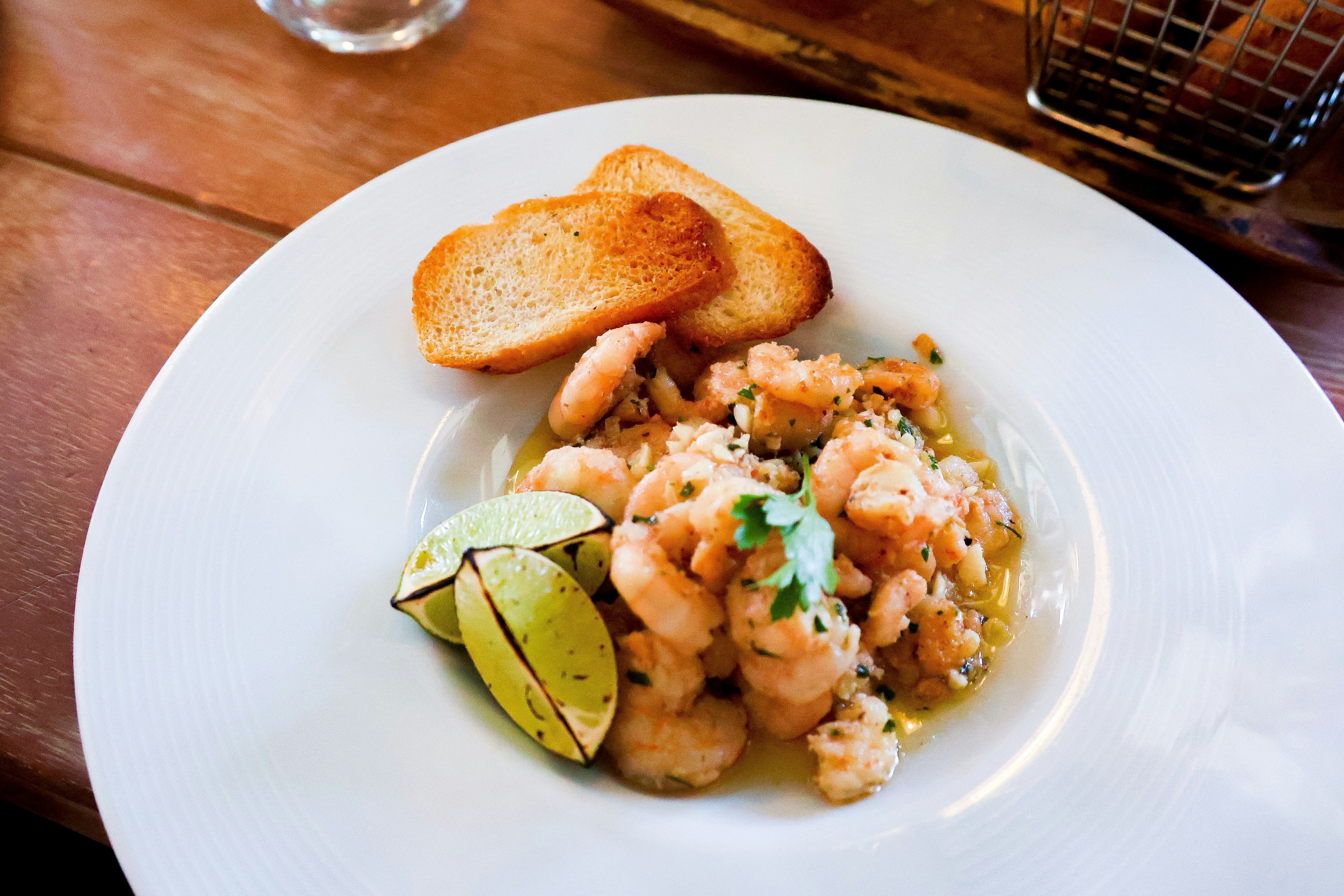 Shrimp ceviche with toast and lime on a plate.