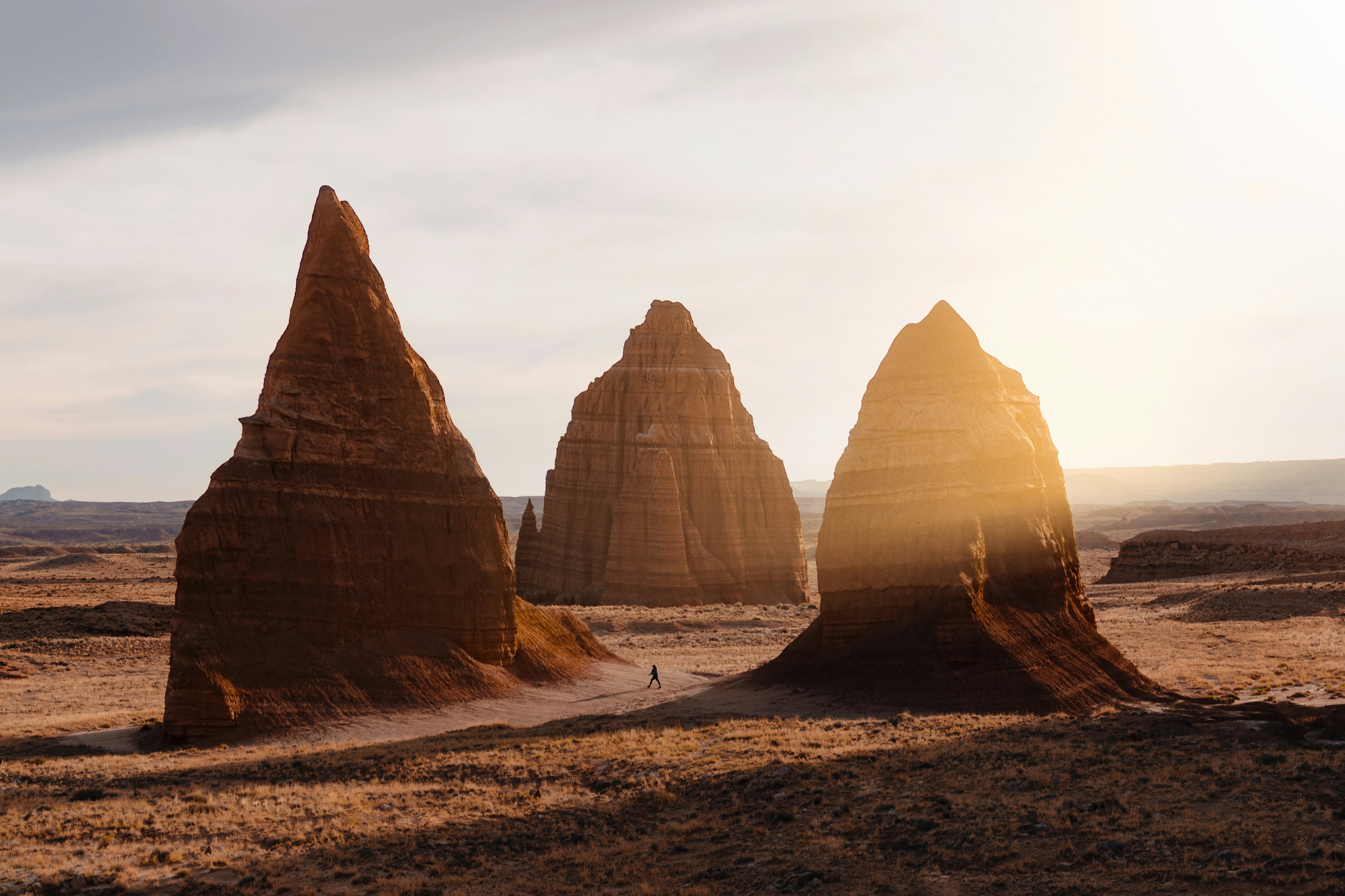 Sun shines through rock formations in a desert.