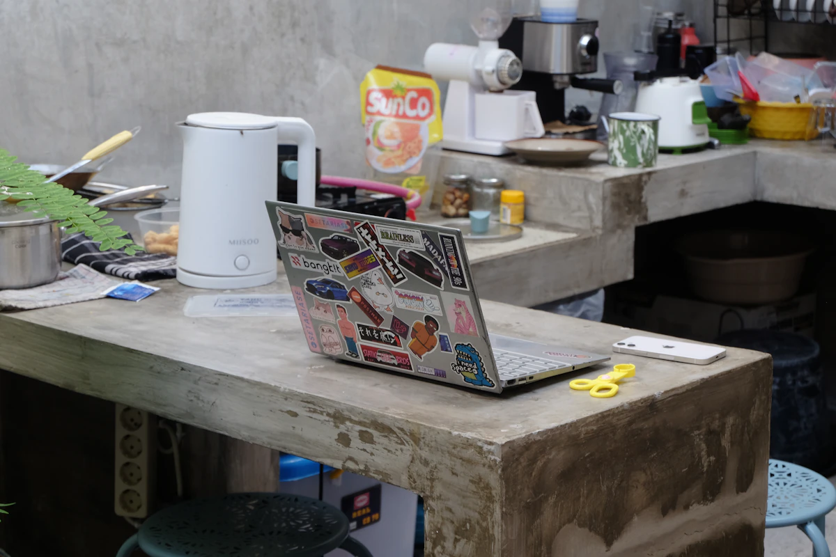 Laptop sits on a messy kitchen counter.