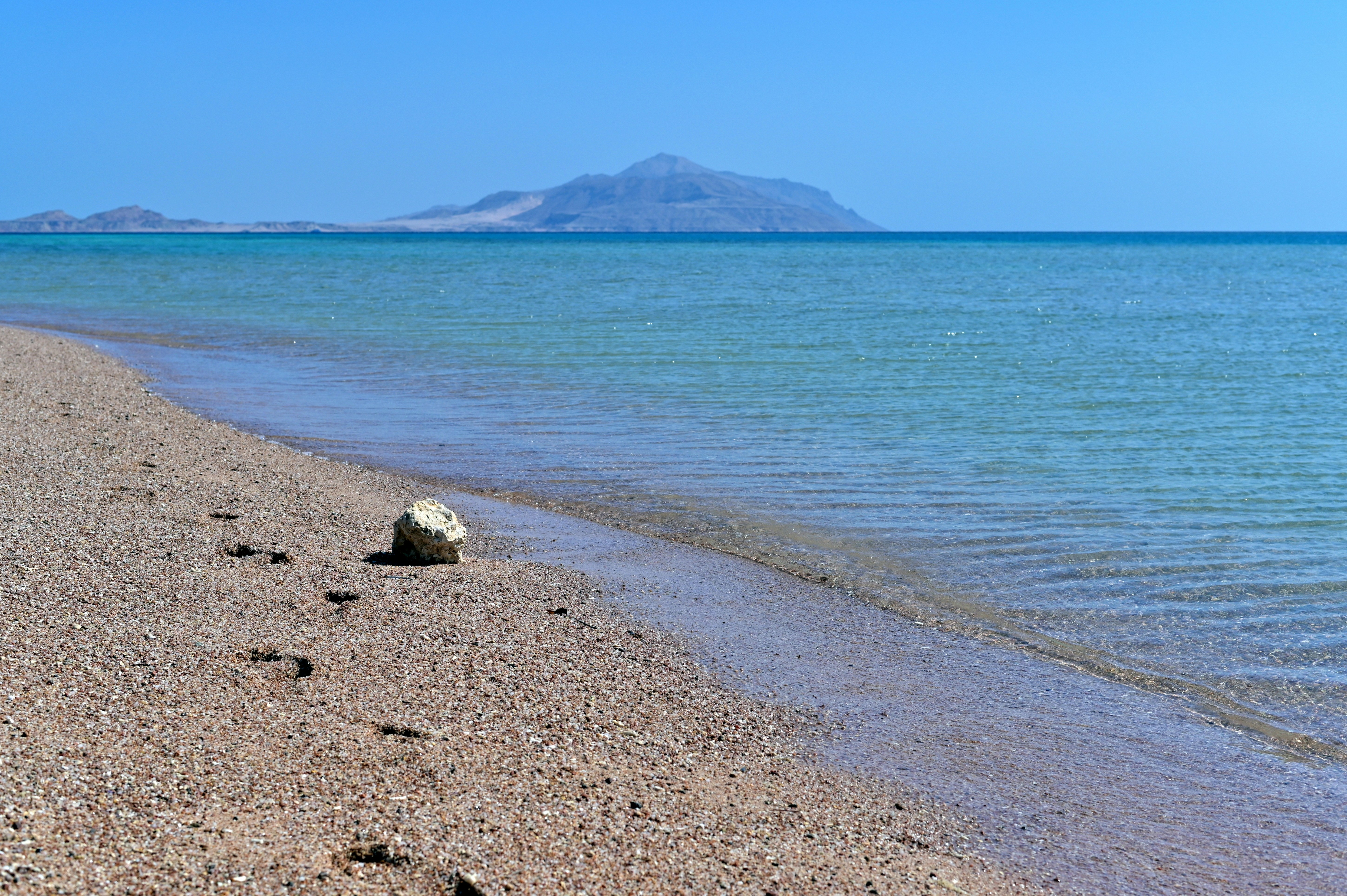 A serene beach with a mountain in the distance.