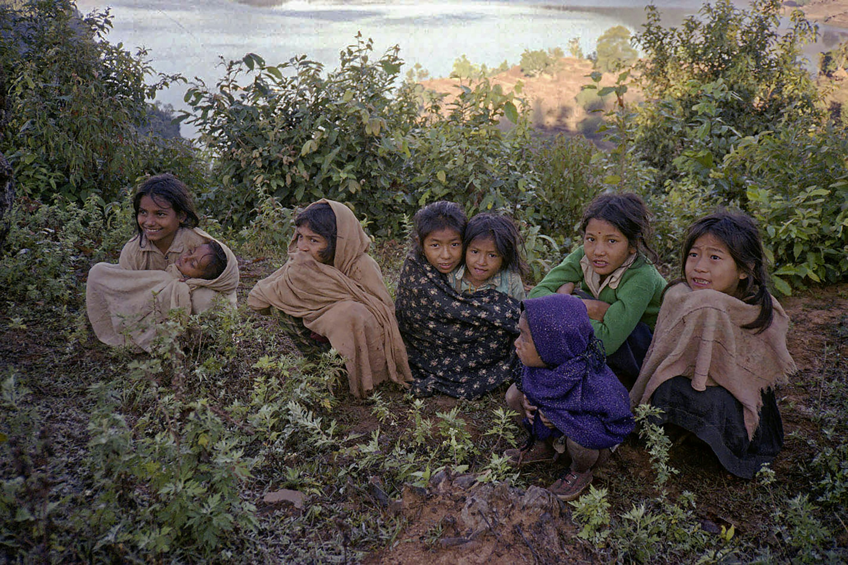 Children huddled together outdoors, looking towards the camera.