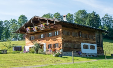 A wooden house stands in a green field.