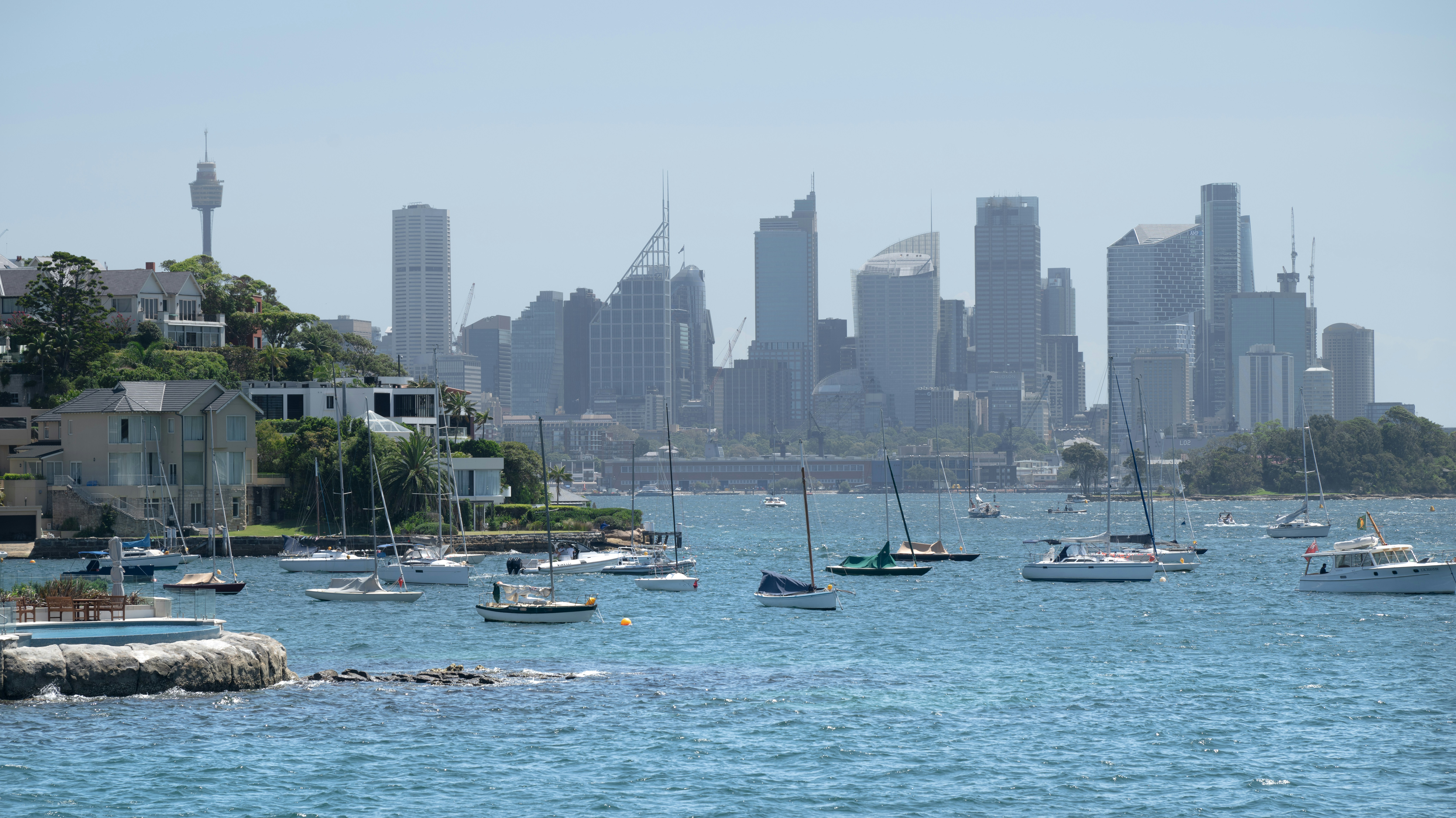 Boats fill harbor with a distant city skyline. (Photo by SOHAM BANERJEE on Unsplash)