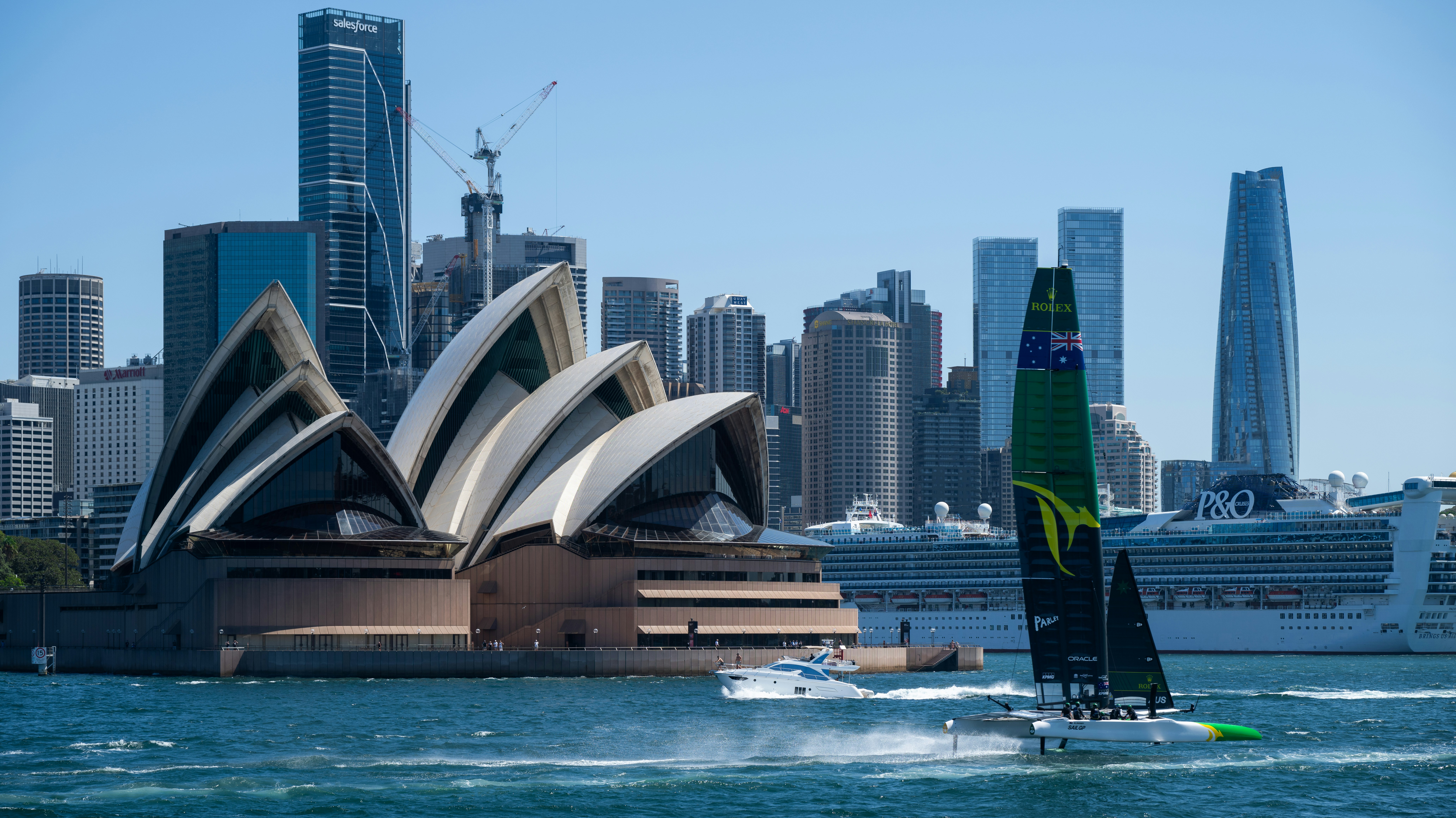 Perahu layar melaju melewati gedung opera sydney dan cakrawala.