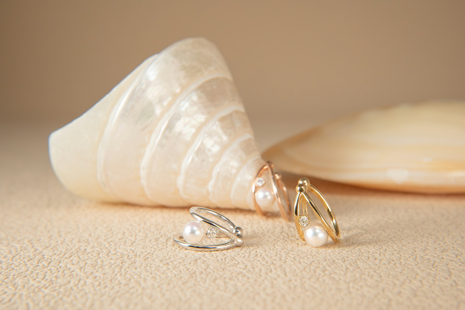 Pearl earrings rest next to a seashell.