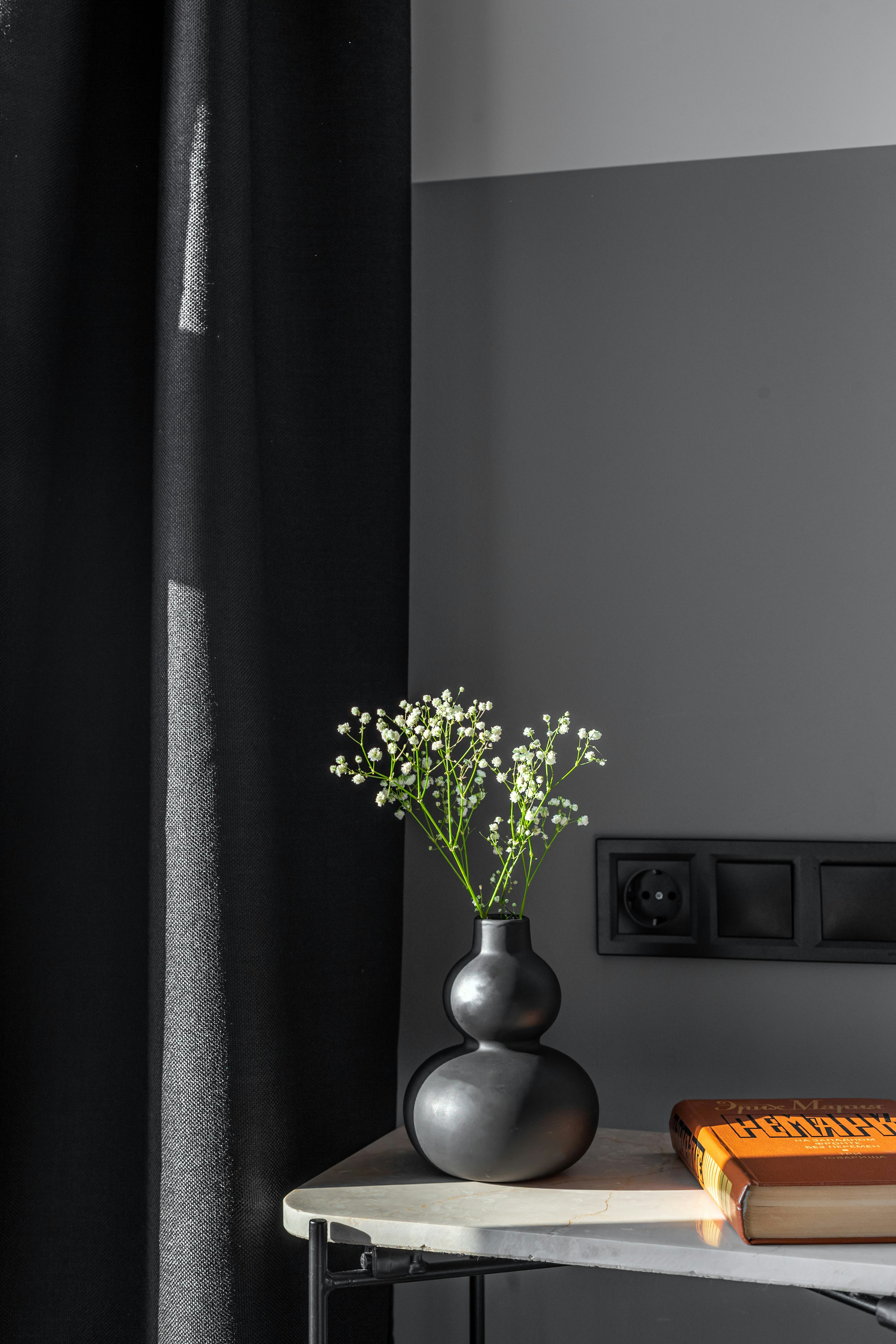 A vase of flowers rests next to a book.