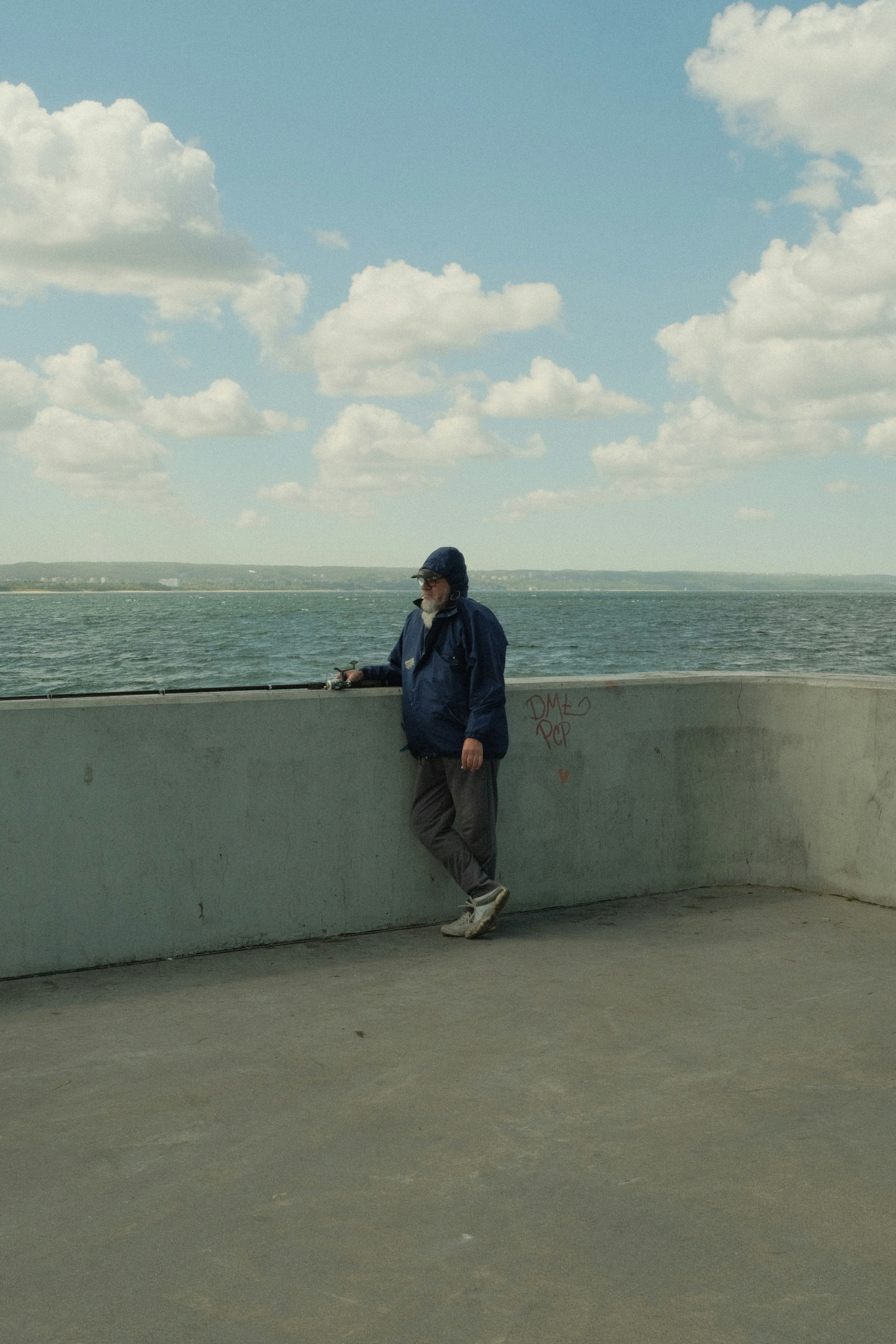 A man stands by the sea, gazing outward.