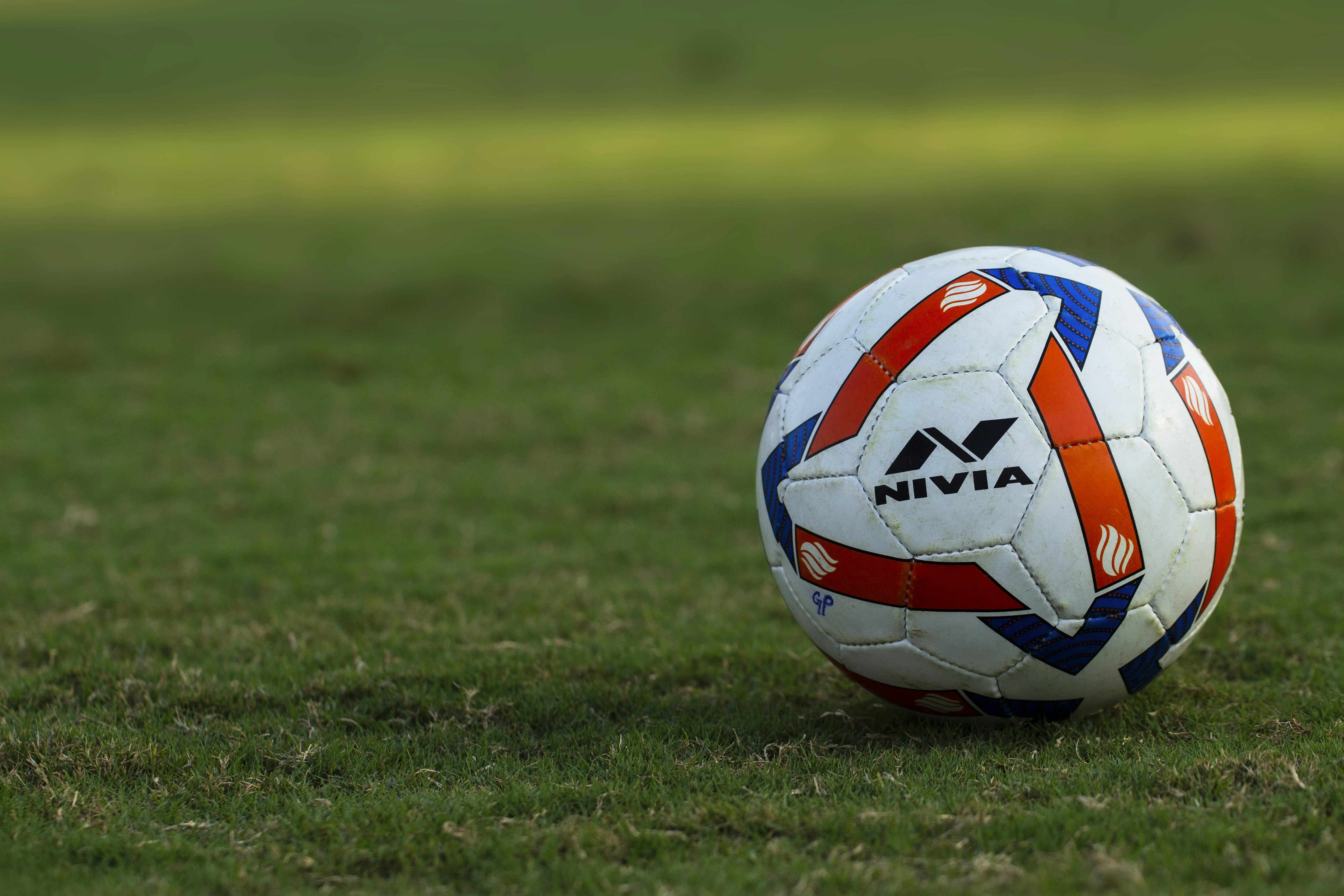 Un ballon de football repose sur l’herbe verte.