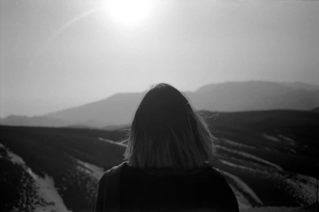 Person gazing at a mountainous landscape.