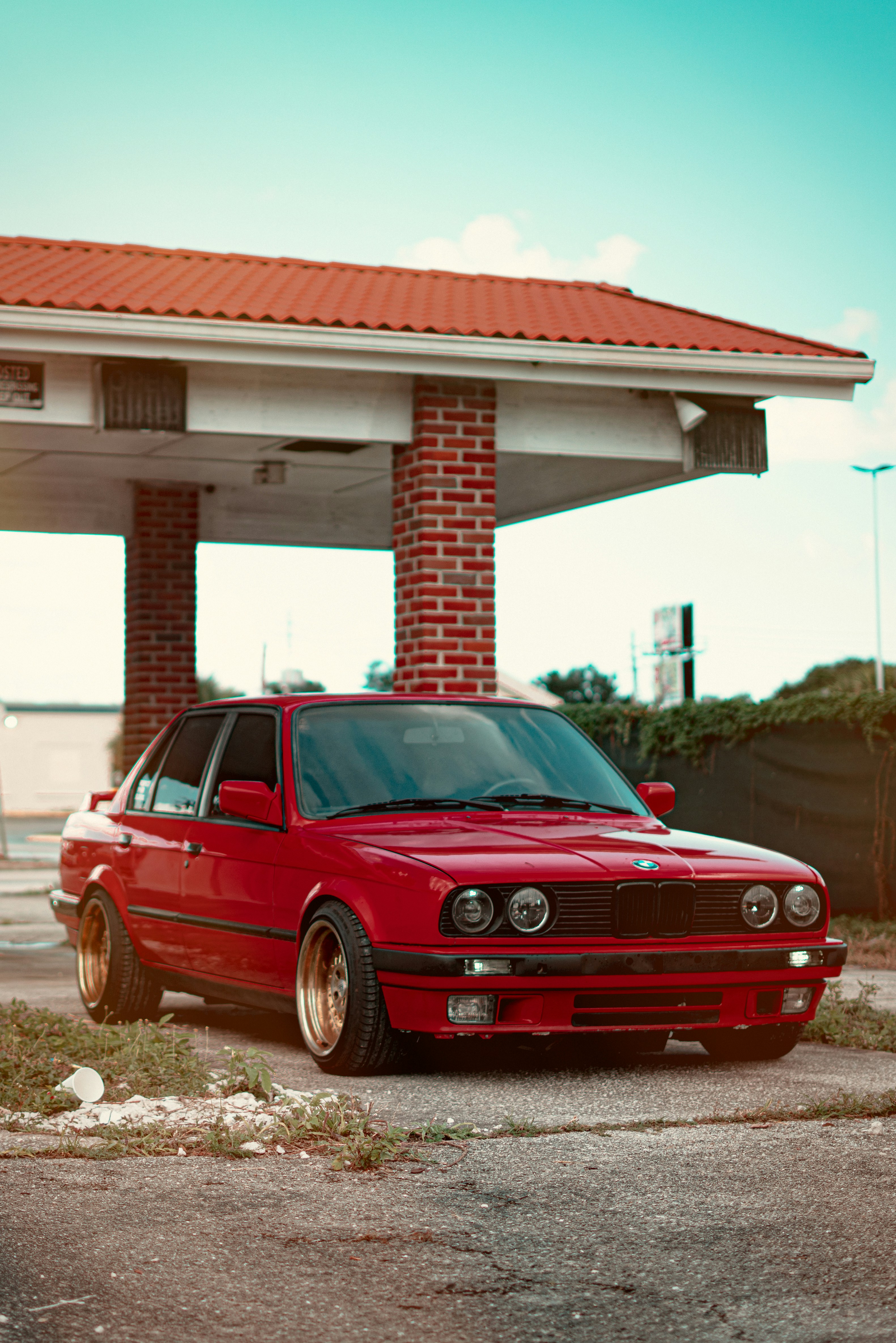 A red car is parked underneath a canopy.