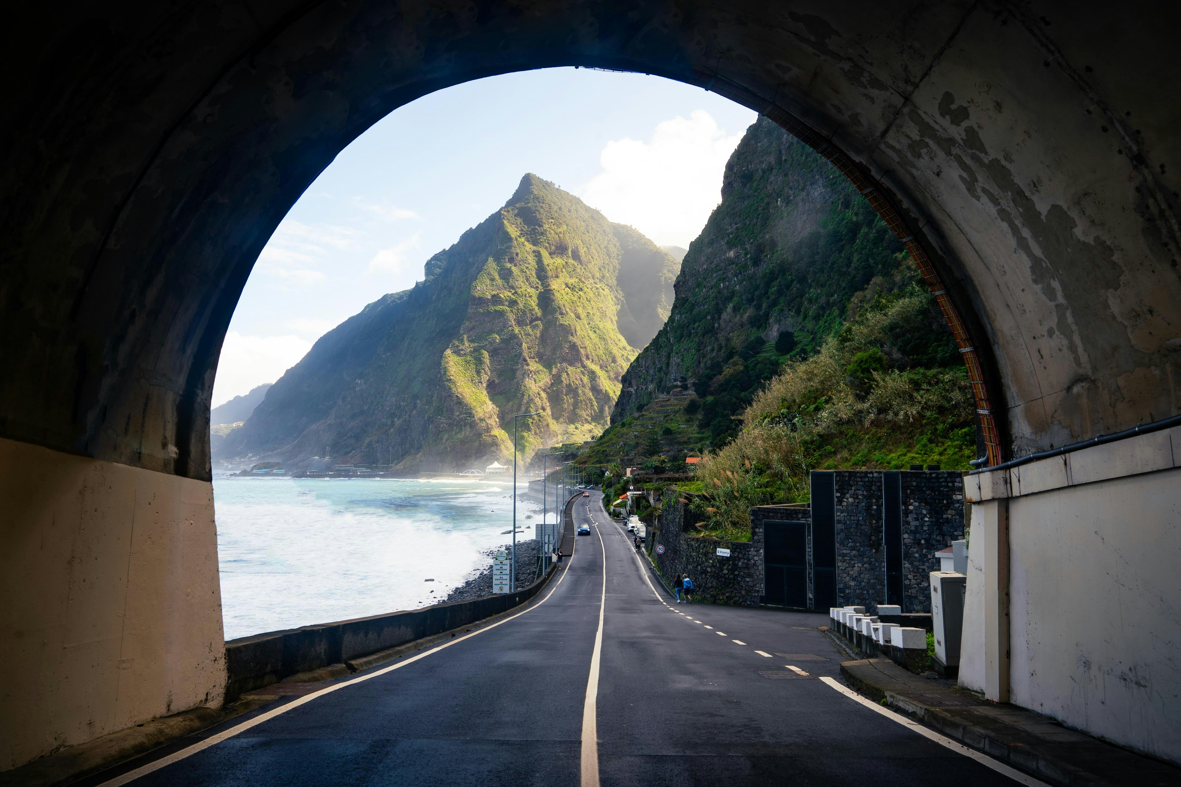 Tunnel frames road and scenic mountains and sea.
