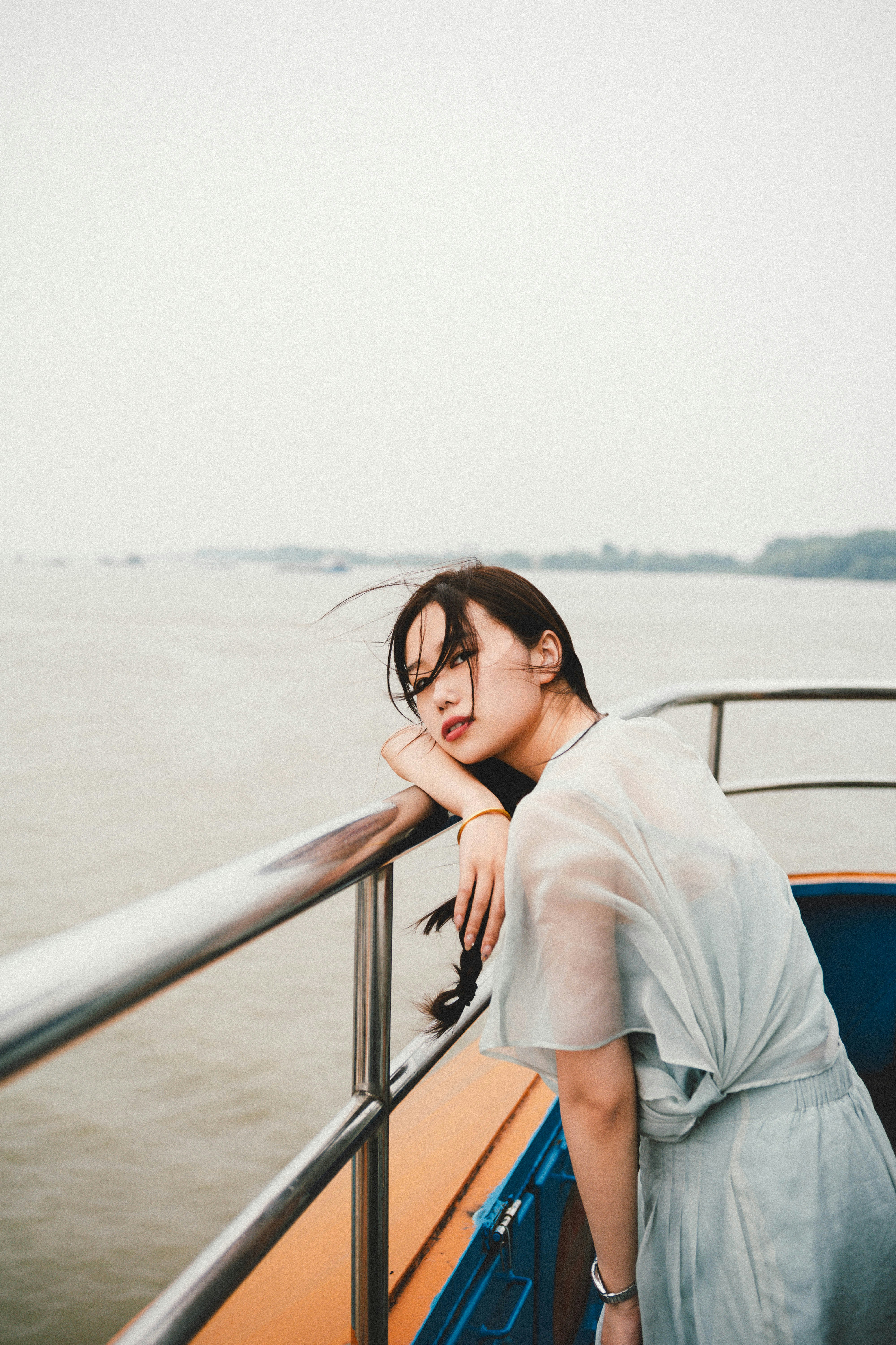 Woman poses on a boat, gazing at the sea.