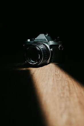 A vintage camera sits on a wooden surface.