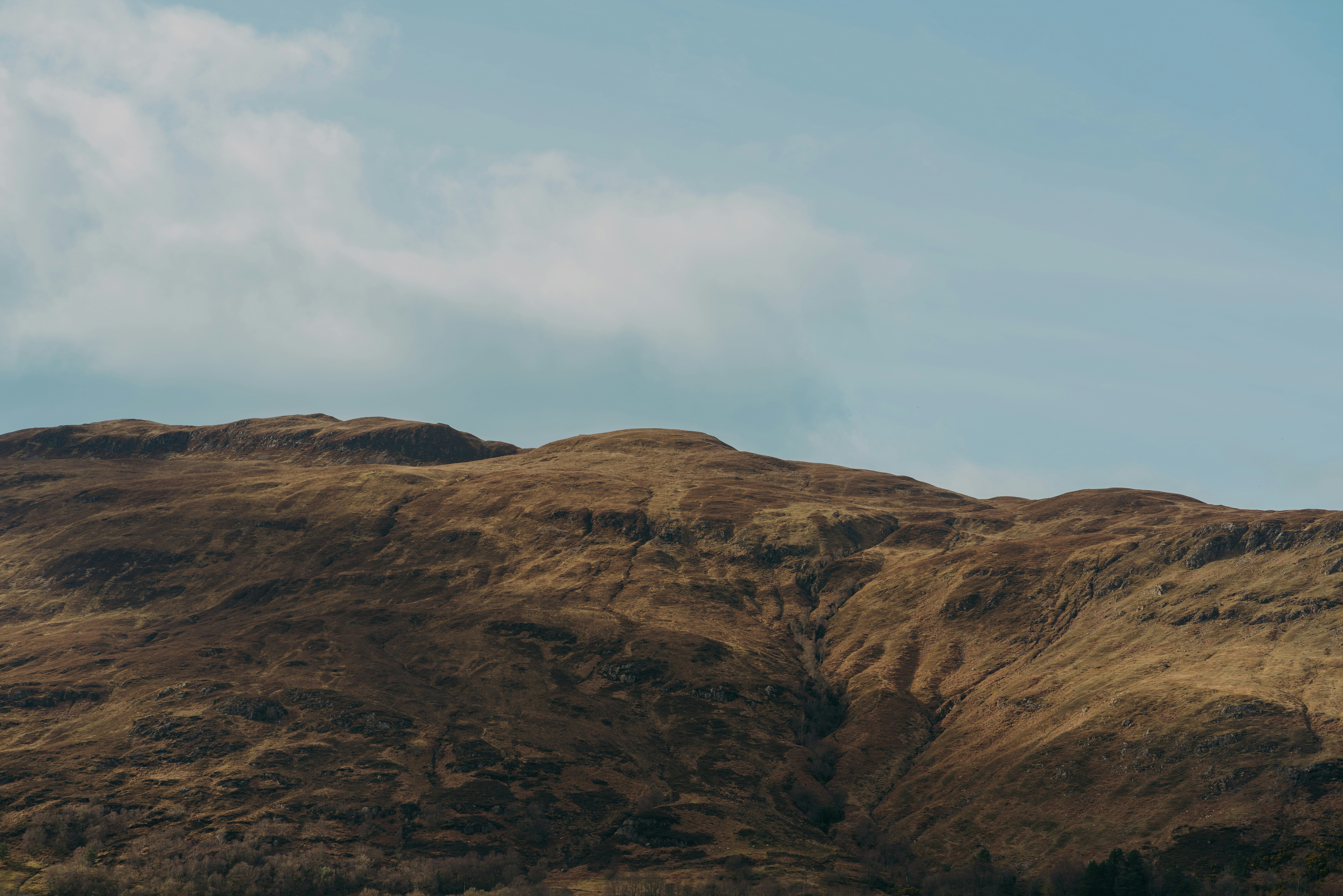 Brown mountains stand beneath a cloudy blue sky.