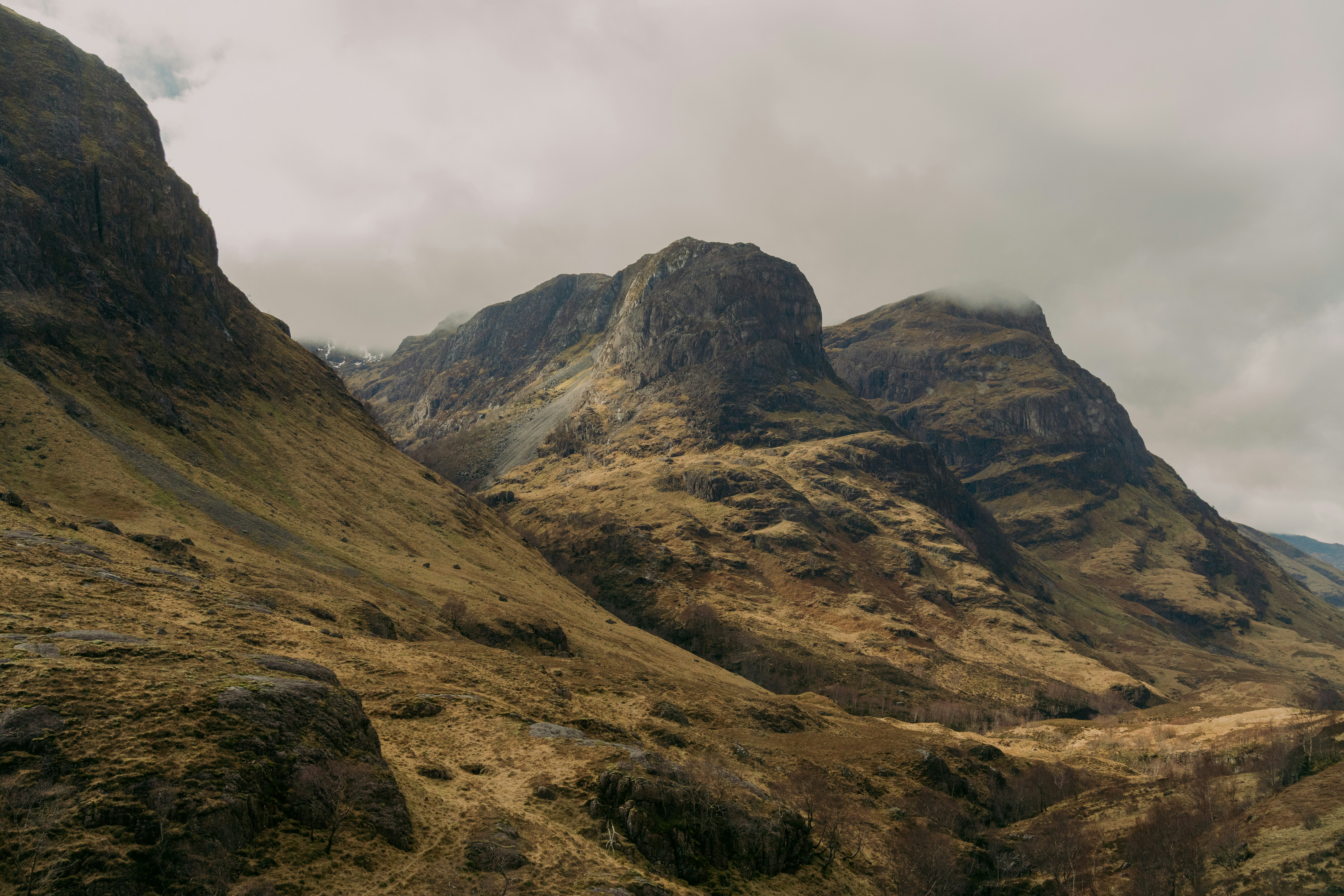 Dramatic mountains rise under a cloudy sky.