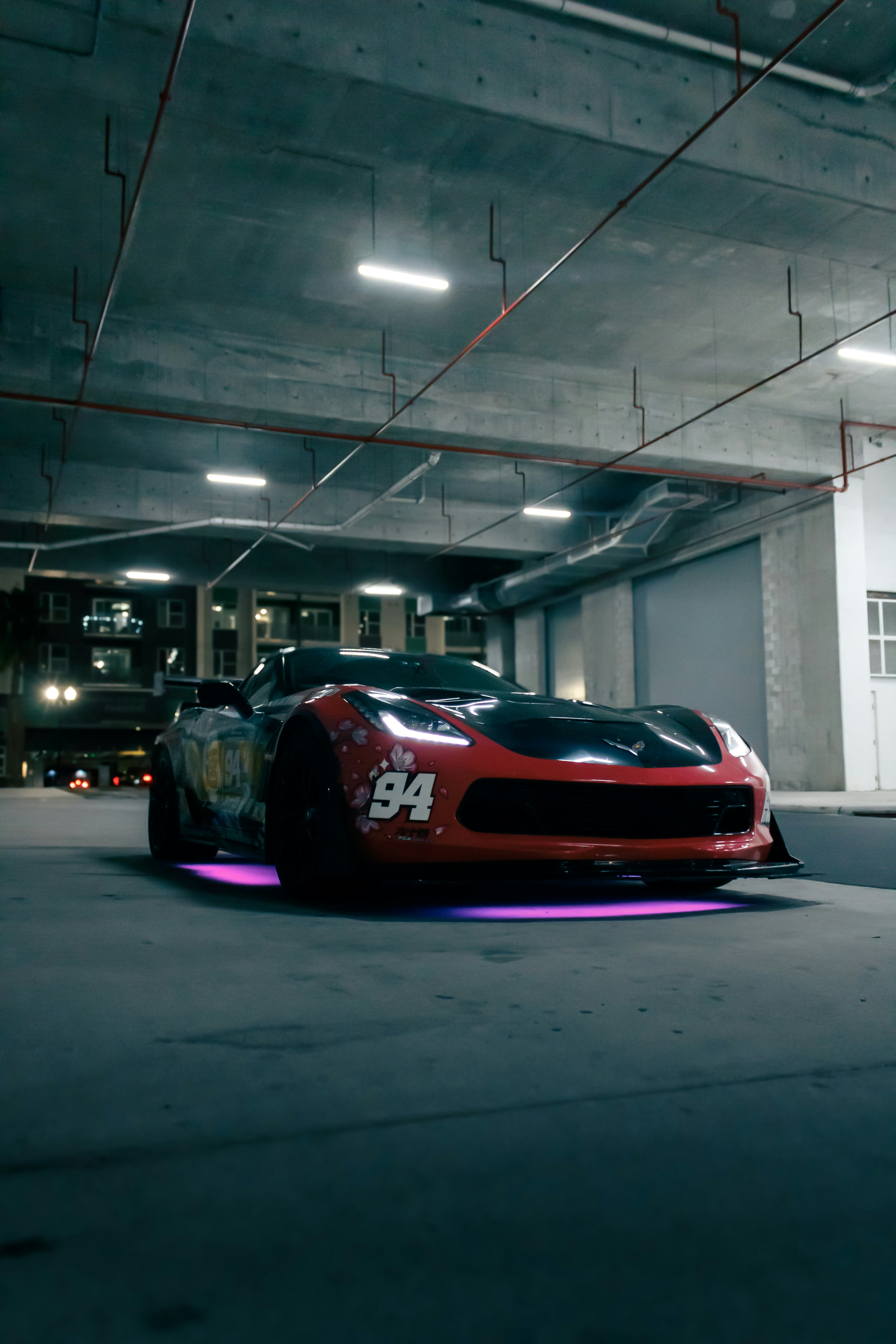 A red and black car is parked indoors.