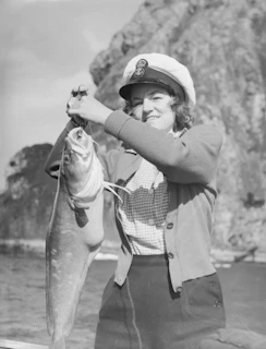 Woman proudly holding a large freshly caught fish