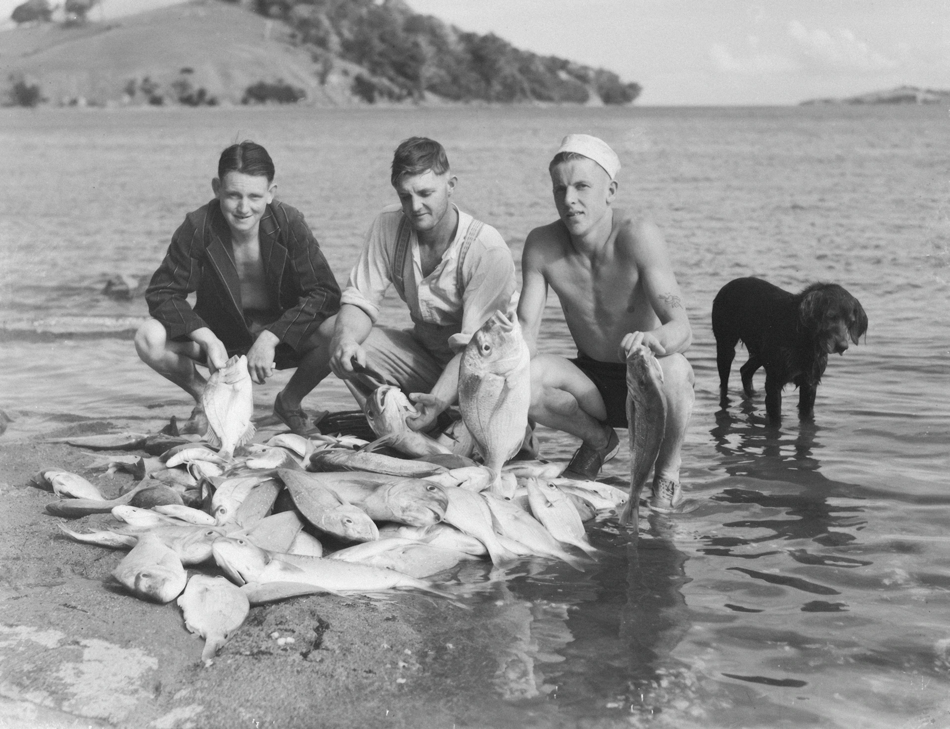 Three men and a dog with a large fish catch