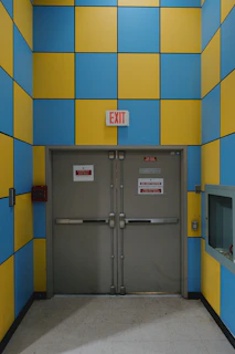 An exit door is framed by blue and yellow tiles.