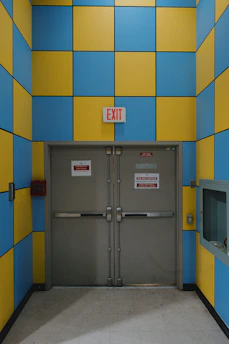 An exit door is framed by blue and yellow tiles.