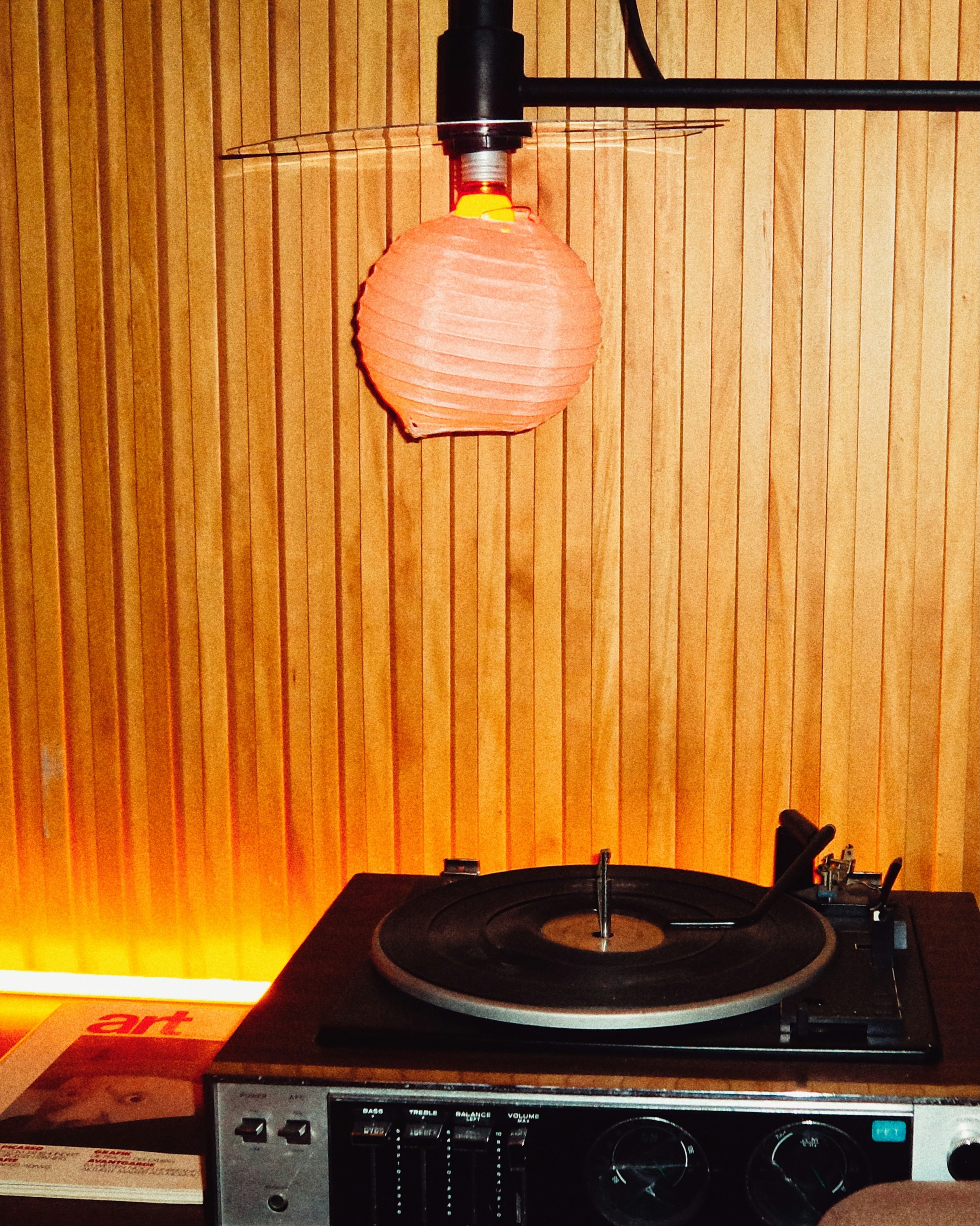 A record player sits below a decorative light.