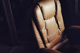 A brown leather chair is lit against darkness.